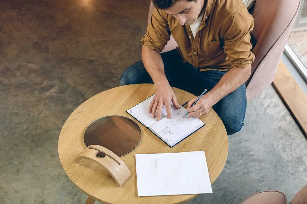Man sitting at a table writing in a notebook