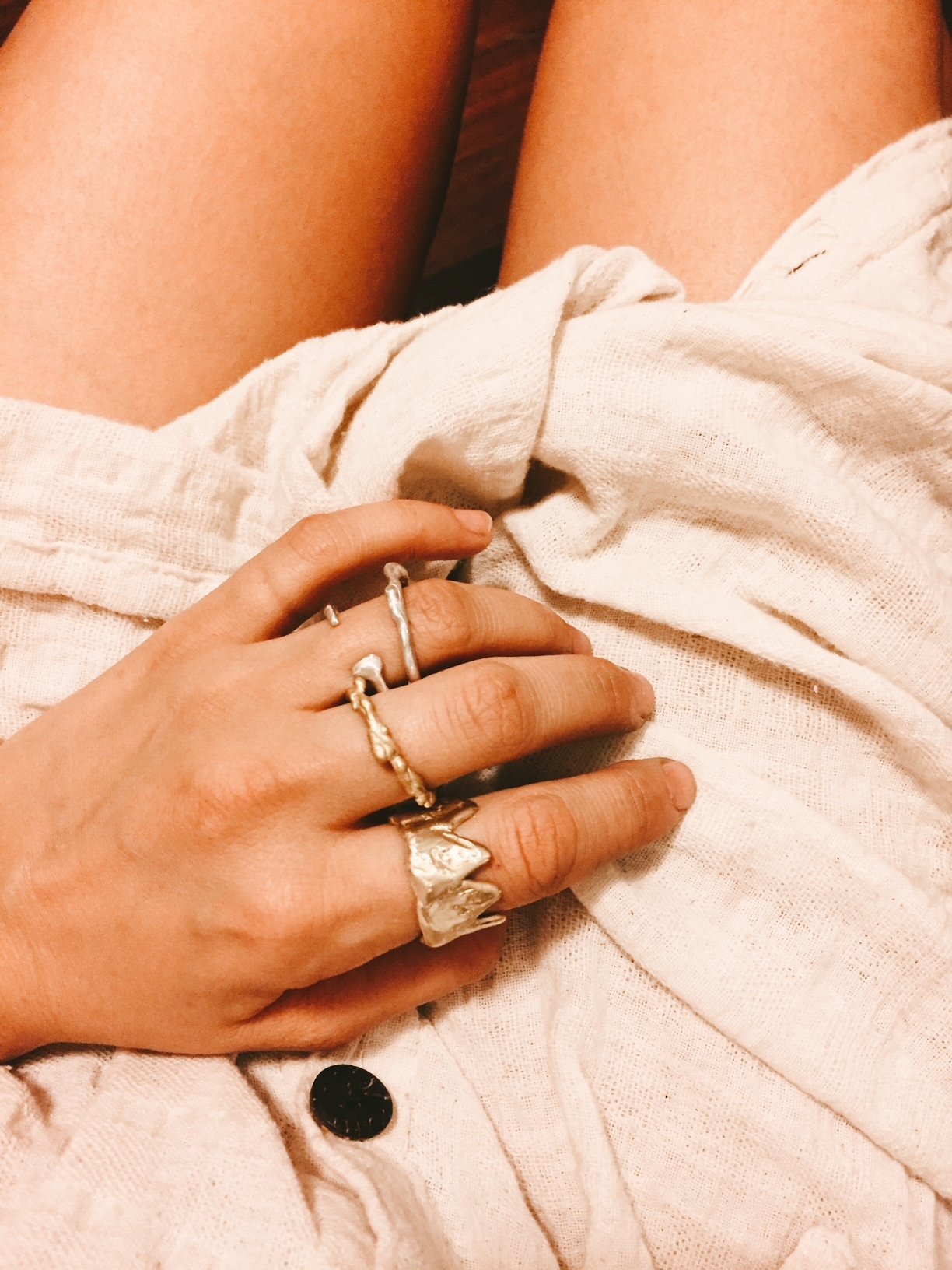 Close-up of a person's hand wearing multiple rings on a light fabric background