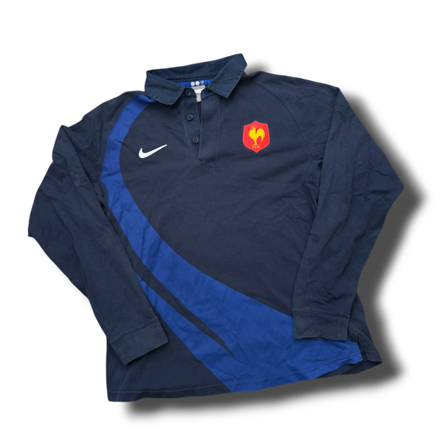 Dark blue sports jersey with a blue swoosh logo on the chest, a red emblem with a yellow rooster and the letters F.F.R. on the left side, and a blue curved stripe across the front.
