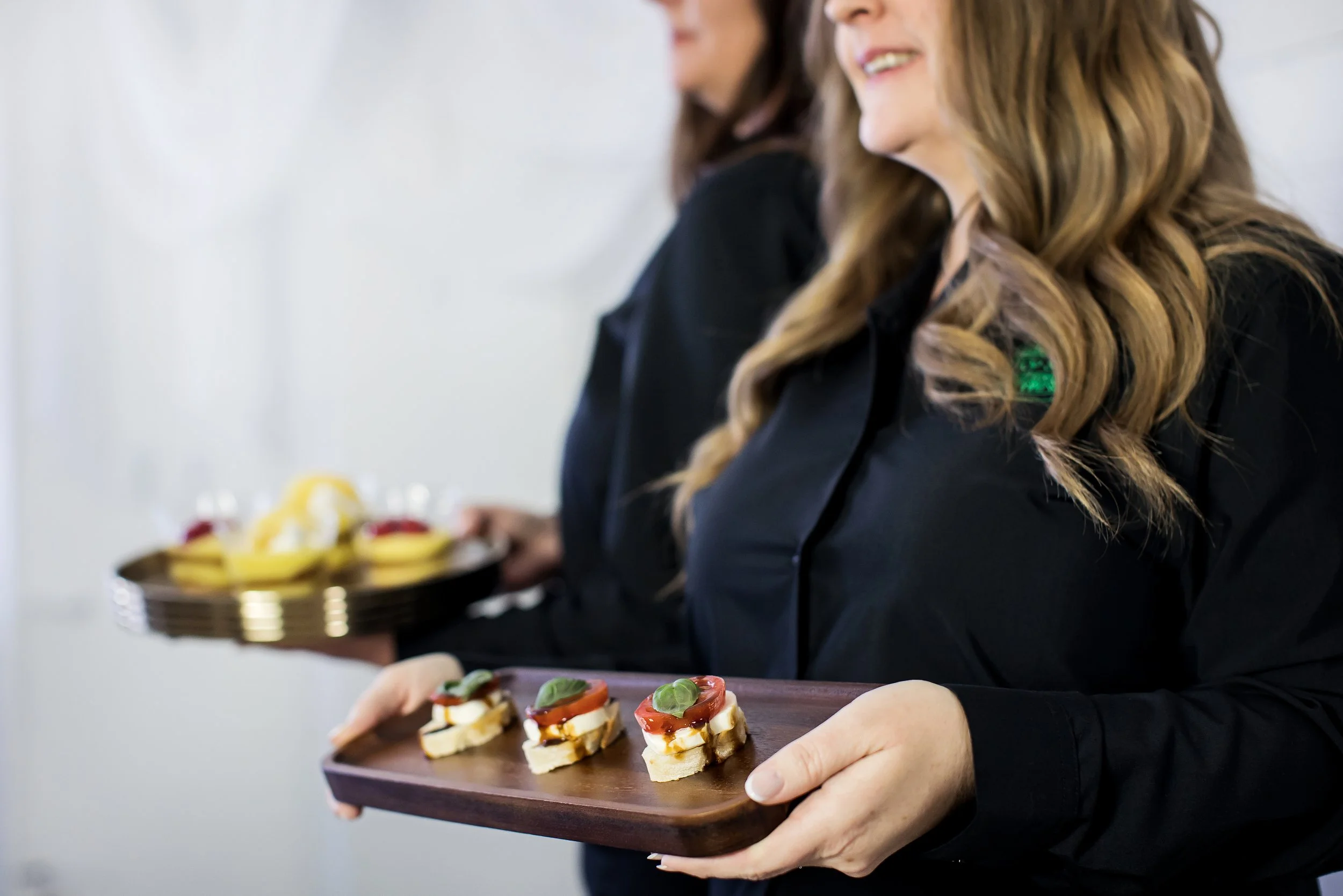 Professional catering staff serving hors d'oeuvres at an event by Top Shelf Cuisine & Cocktails