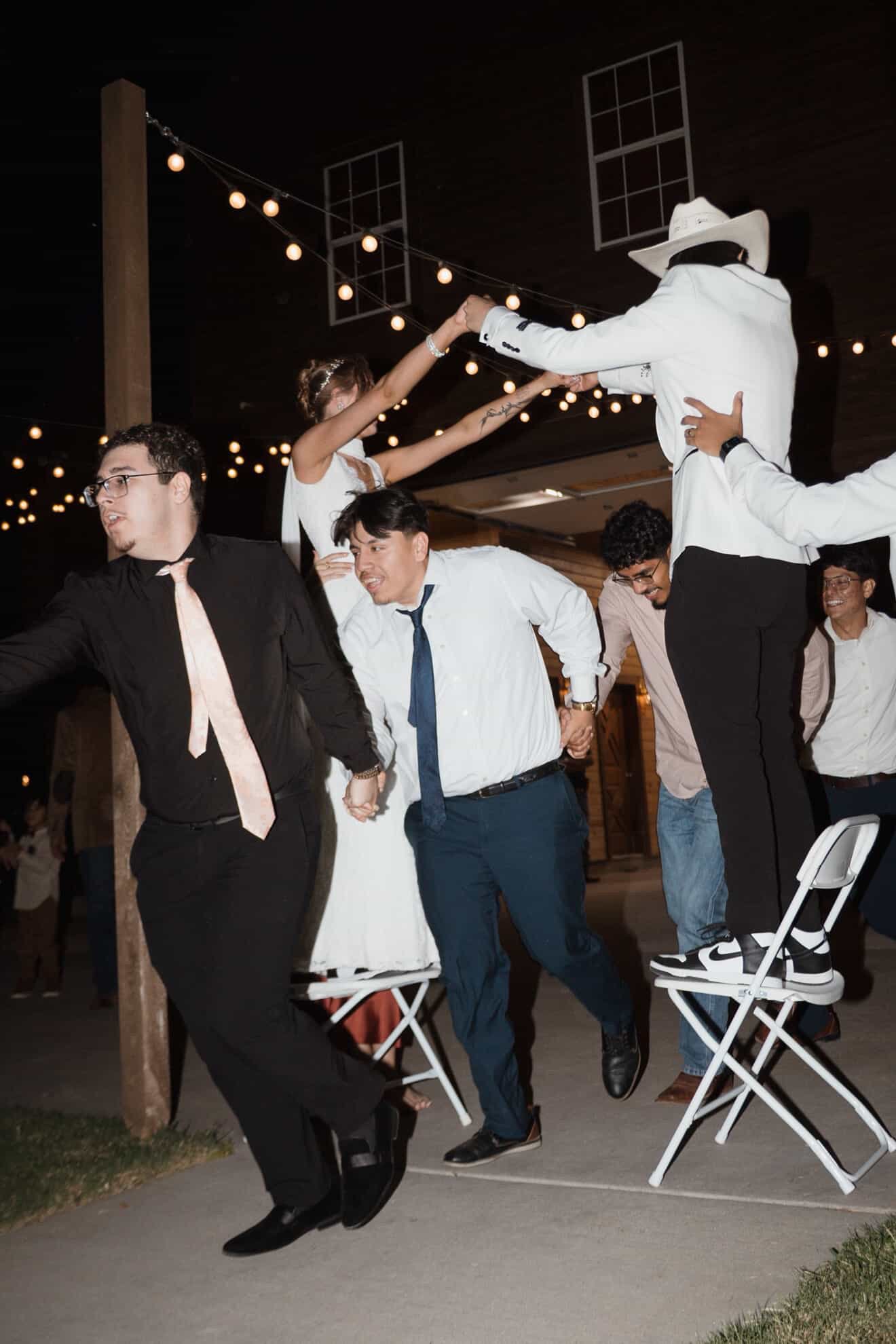 Guests celebrating on the dance floor during Ellie and Ricardo’s wedding reception at Express Ranch in Yukon, Oklahoma, under string lights during an energetic evening celebration.
