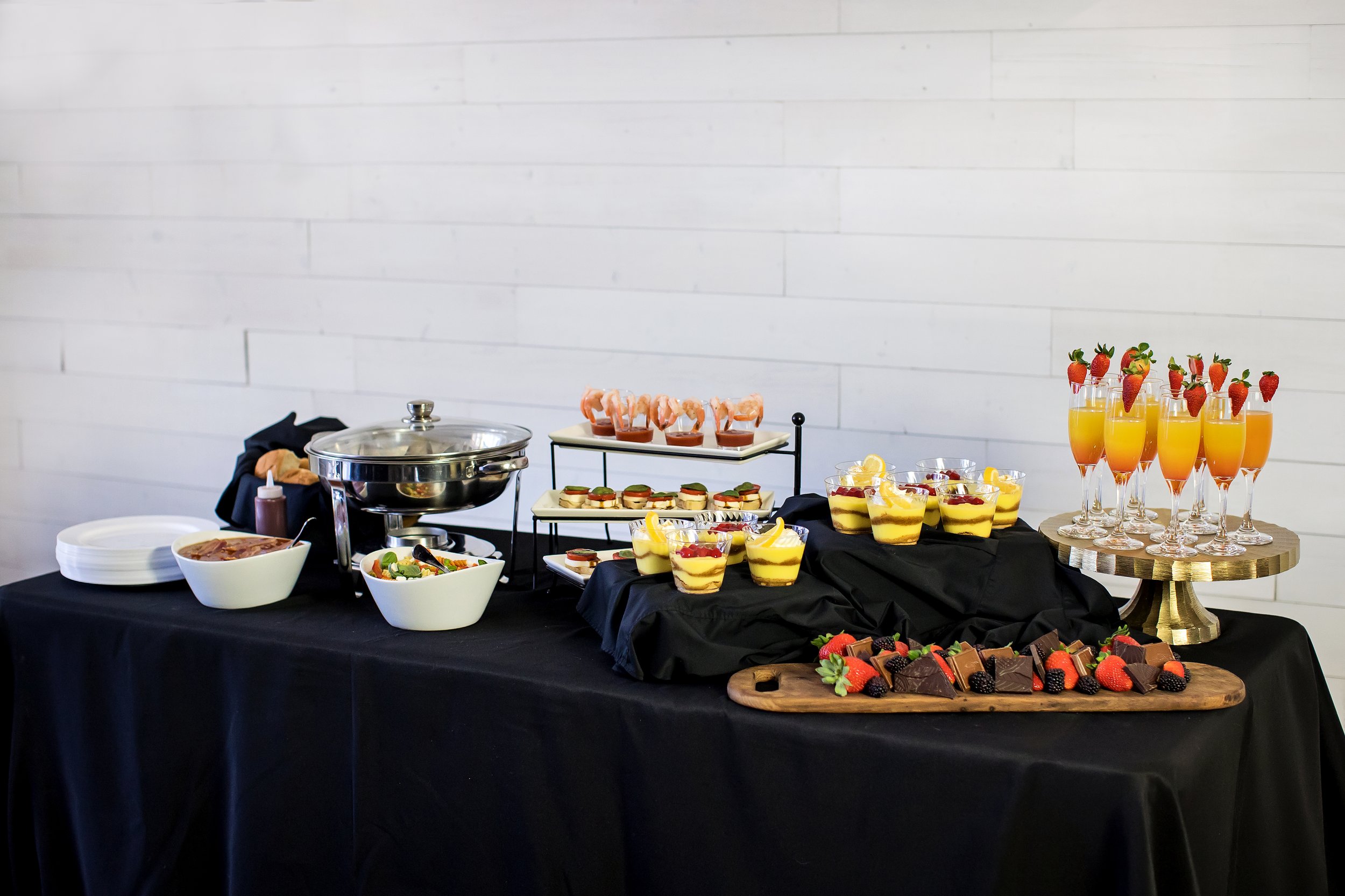 Luxury catering and bartending display at an Oklahoma City event featuring plated appetizers, desserts, and champagne cocktails, professionally styled for an upscale celebration.