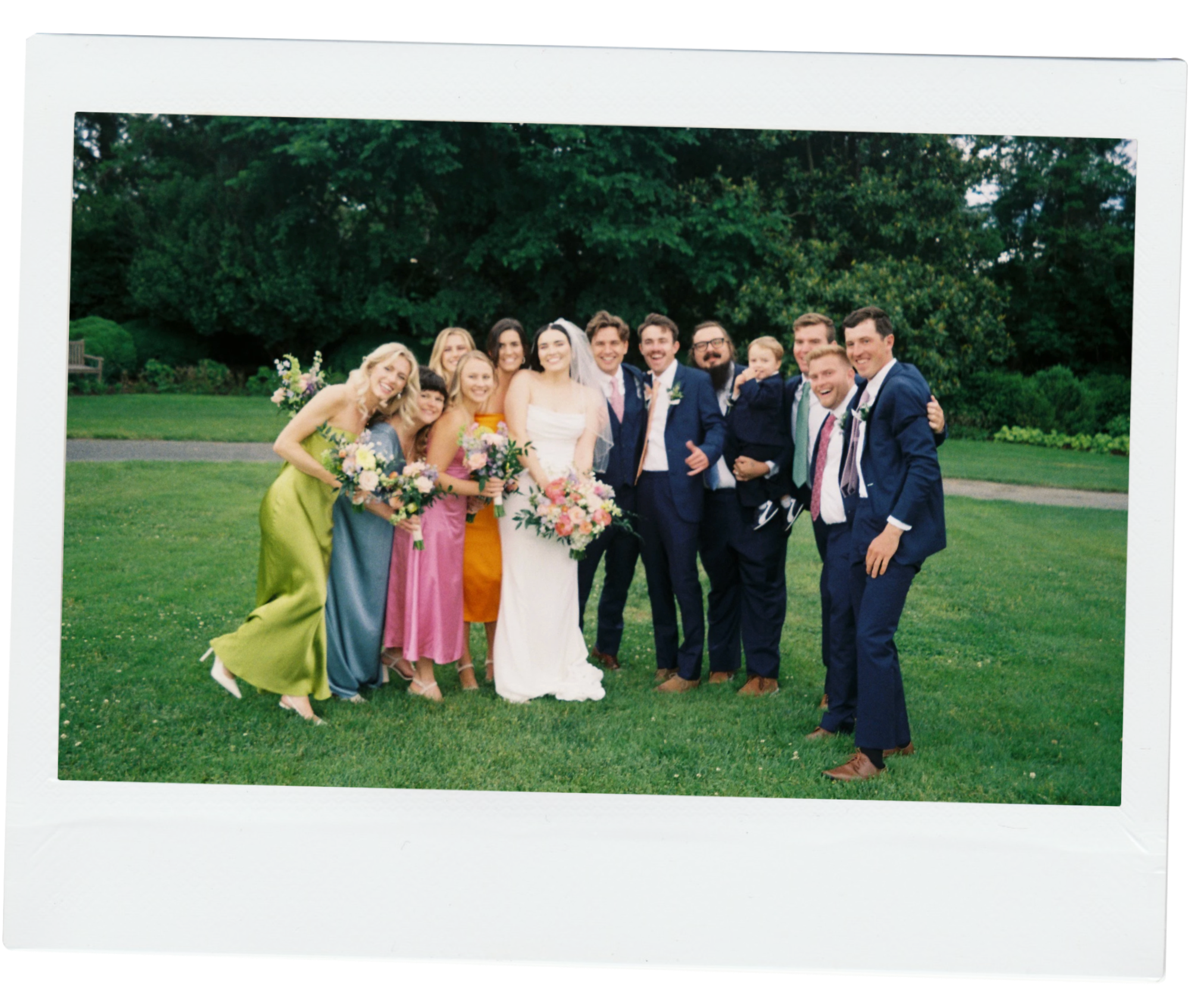 A film photo of the bride and groom and their entire wedding party smiling at the camera. The image was taken at a wedding in Alexandria, Virginia.