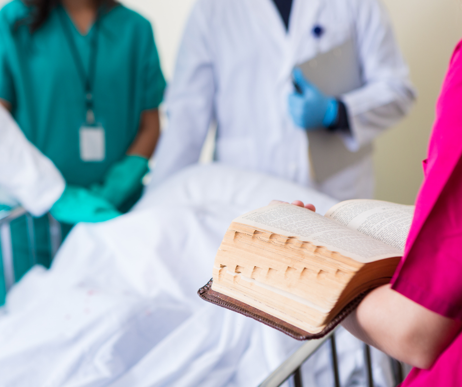 Healthcare professionals in scrubs and lab coats around a hospital bed with one person holding an open book.