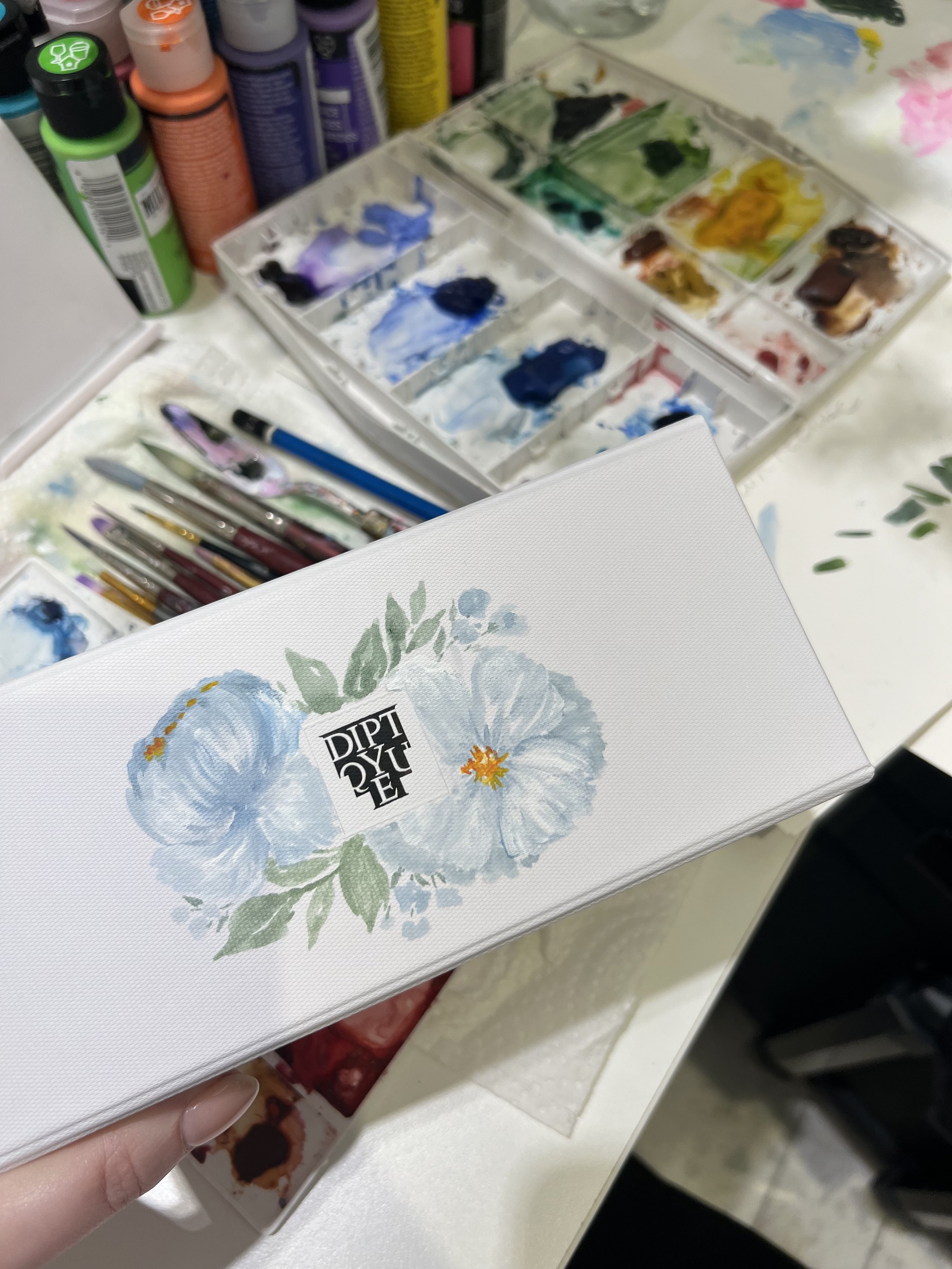 blue-and-white-flowers-painting-on-small-diptyque-box-in-acrylic-and-watercolor-paint.jpeg
