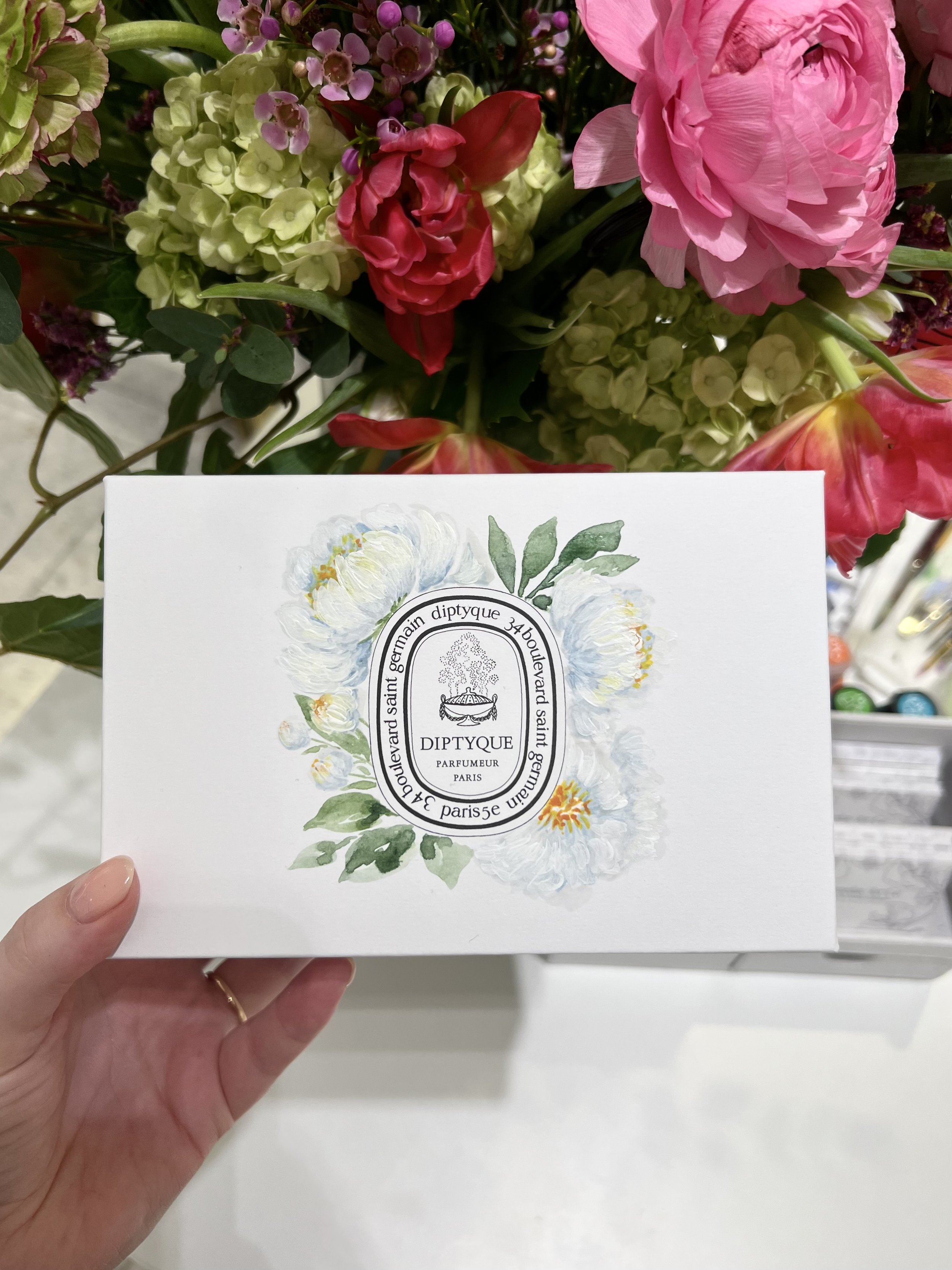 live-event-artist-holding-diptyque-box-with-white-peony-painting.jpeg