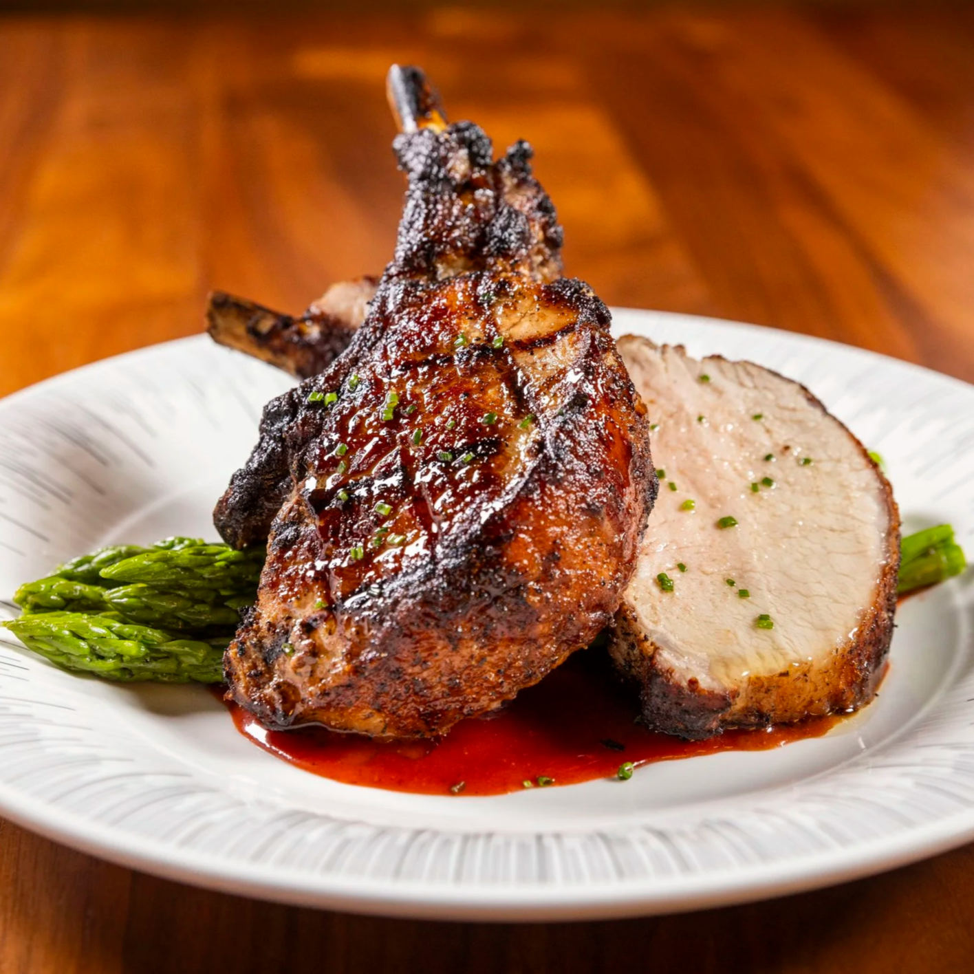 Roasted pork chop with sauce and asparagus on a white plate