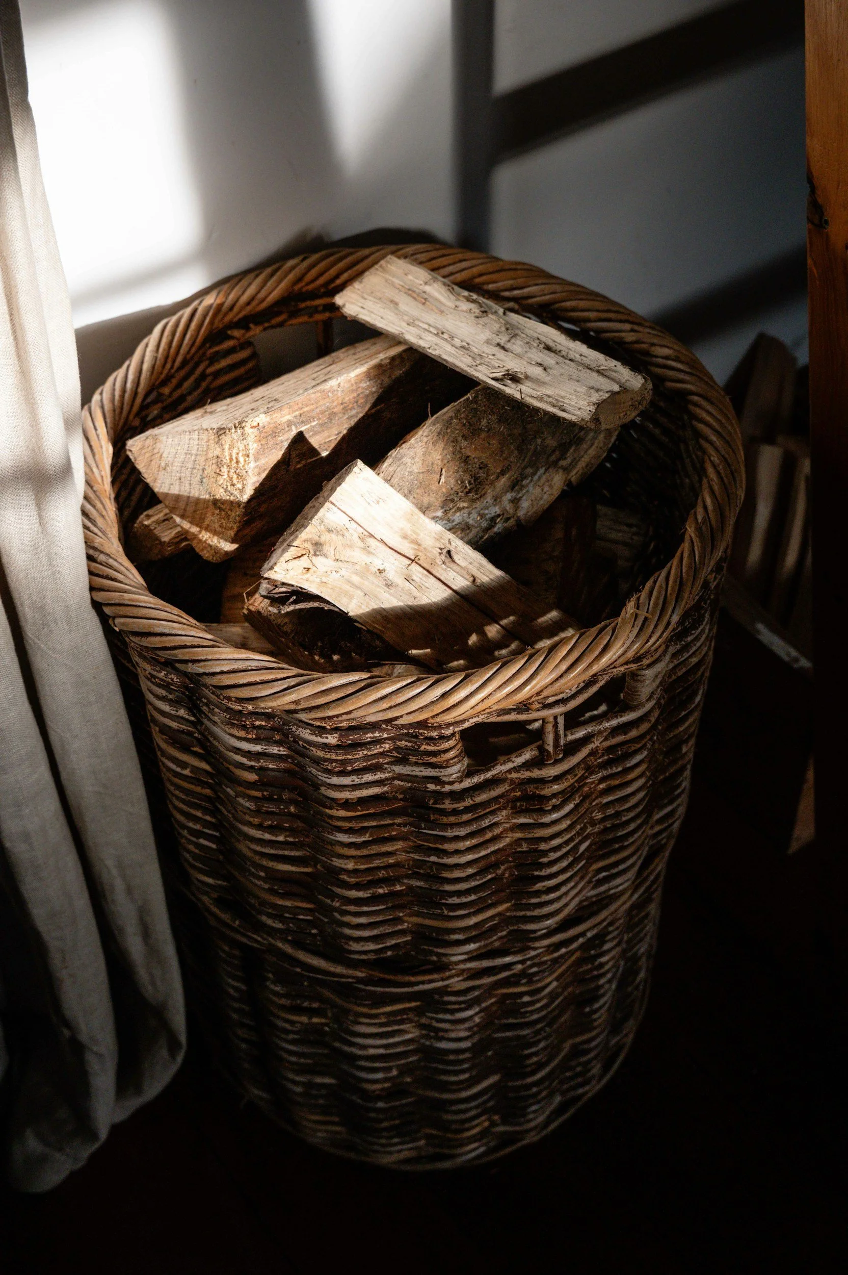 firewood, woven basket, brown, black, gray, light, drapes, beige