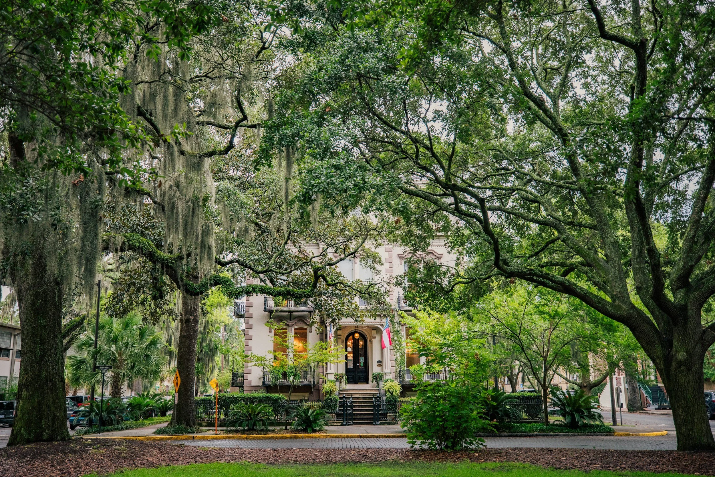 Home, park, town square, historic homes, trees, flag, black door, lantern, steps, iron gate, balcony, street signs, cobblestone streets, green, brown, red, white, blue, black, yellow, black