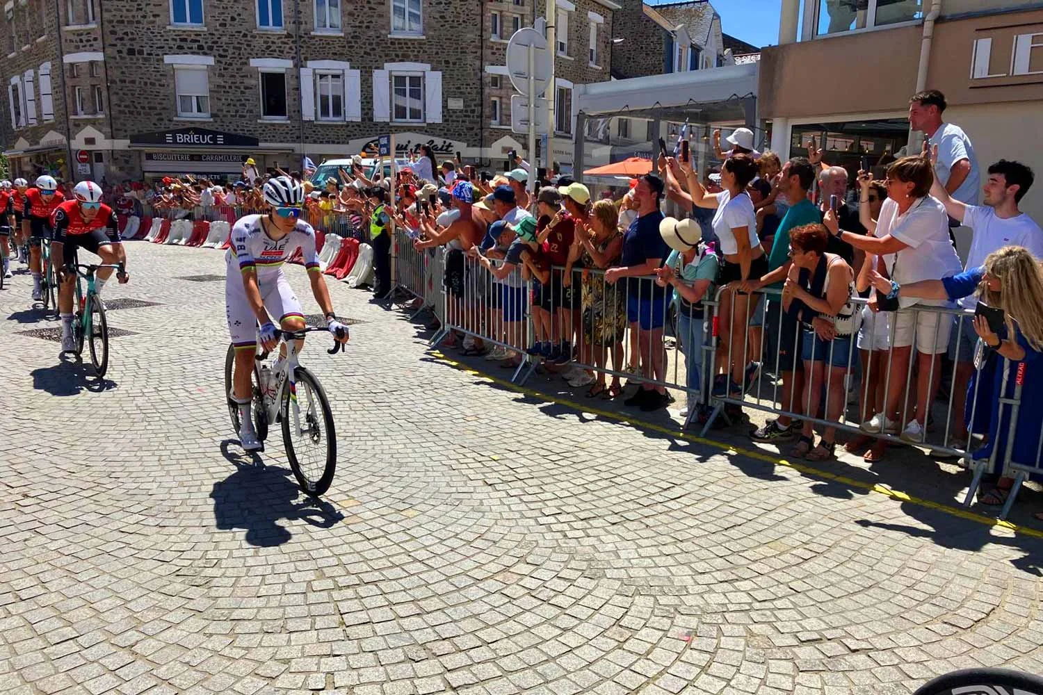 World Champion Tadej Pogacar racing through a crowd of spectators at the Tour de France. 