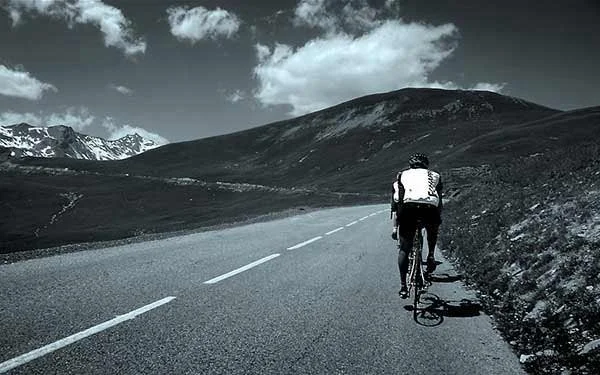 Velo Echappe clients climbing the Col du Galibier in the French Alps. Black and white photo. 