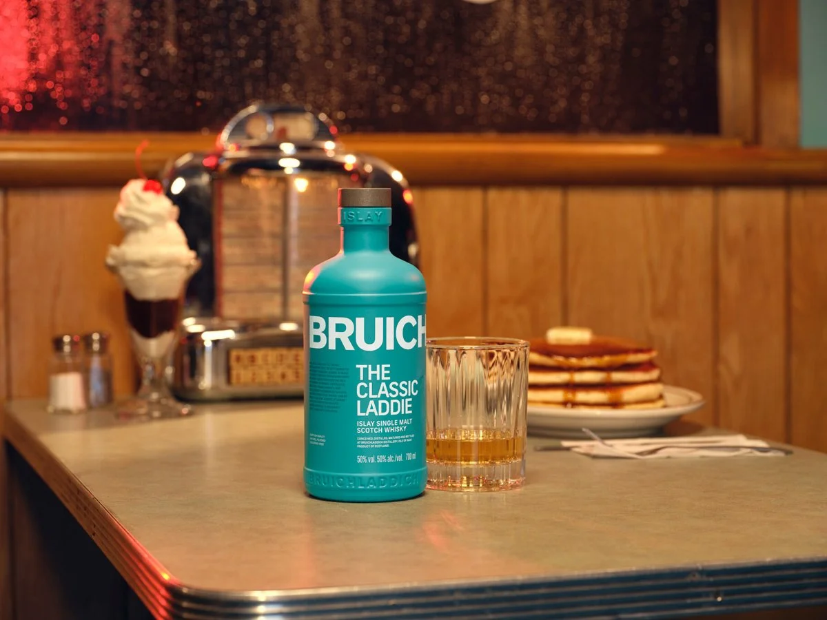 A perfect pour of Bruichladdich scotch. A fluffy stack of pancakes and a sweet hot fudge sundae. Setting is a diner on a rainy night. Food and beverage styled by David Probasco of DP Styling in Los Angeles California. 