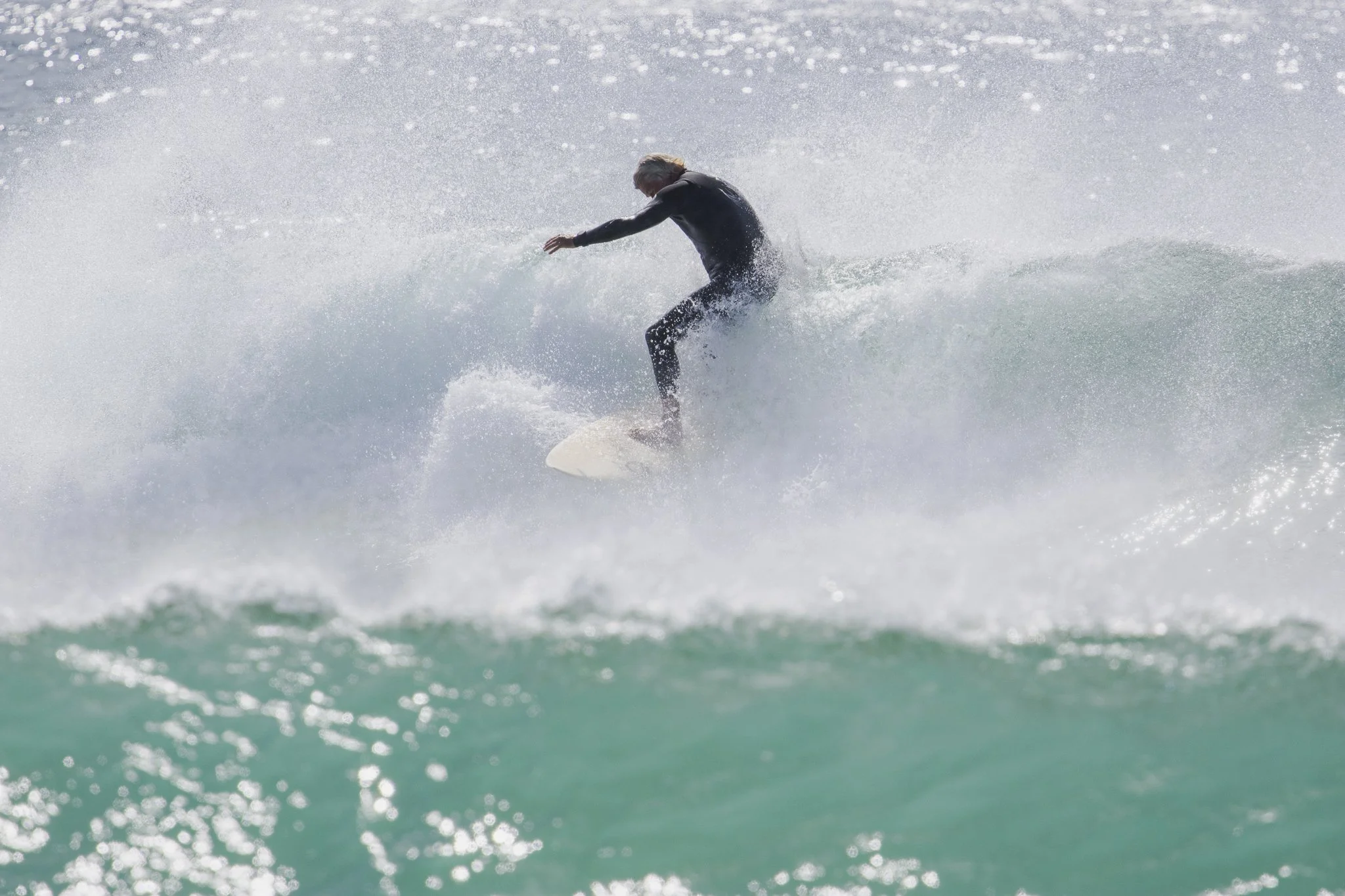 Person surfing on a wave wearing a black wetsuit.