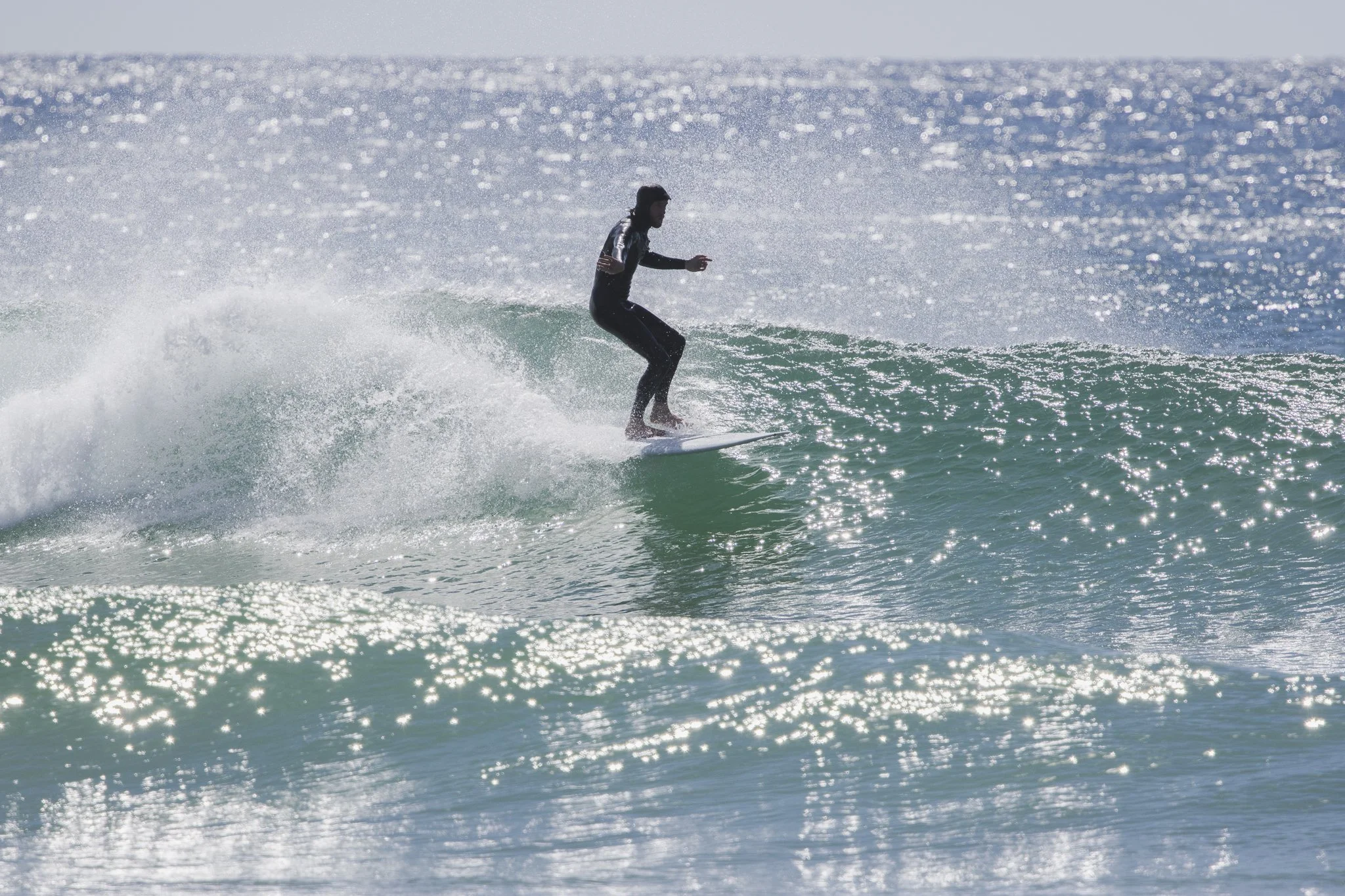 A person wearing a wetsuit surfing on a small wave in the ocean.