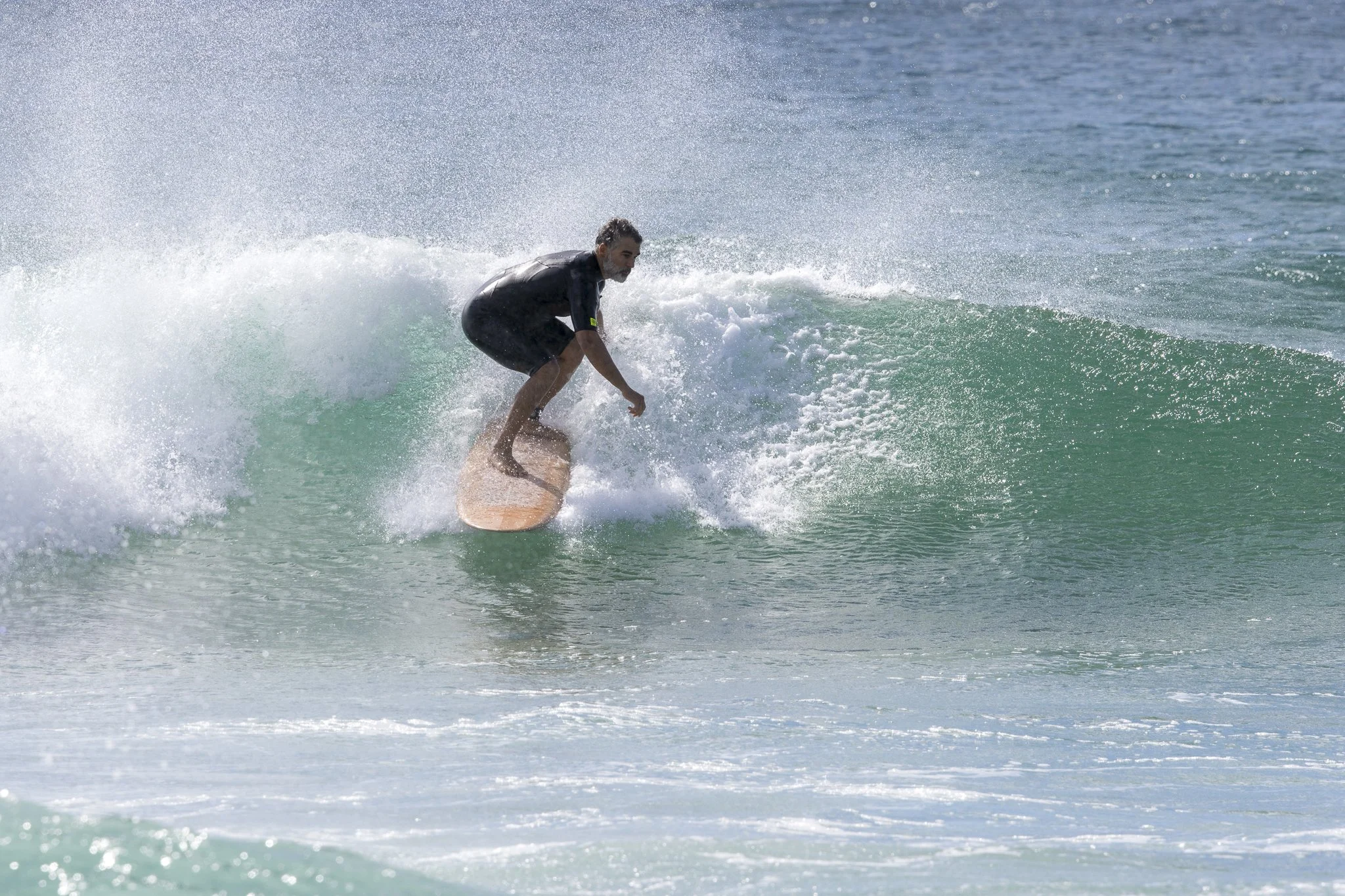 A man surfing on a small wave at the beach.