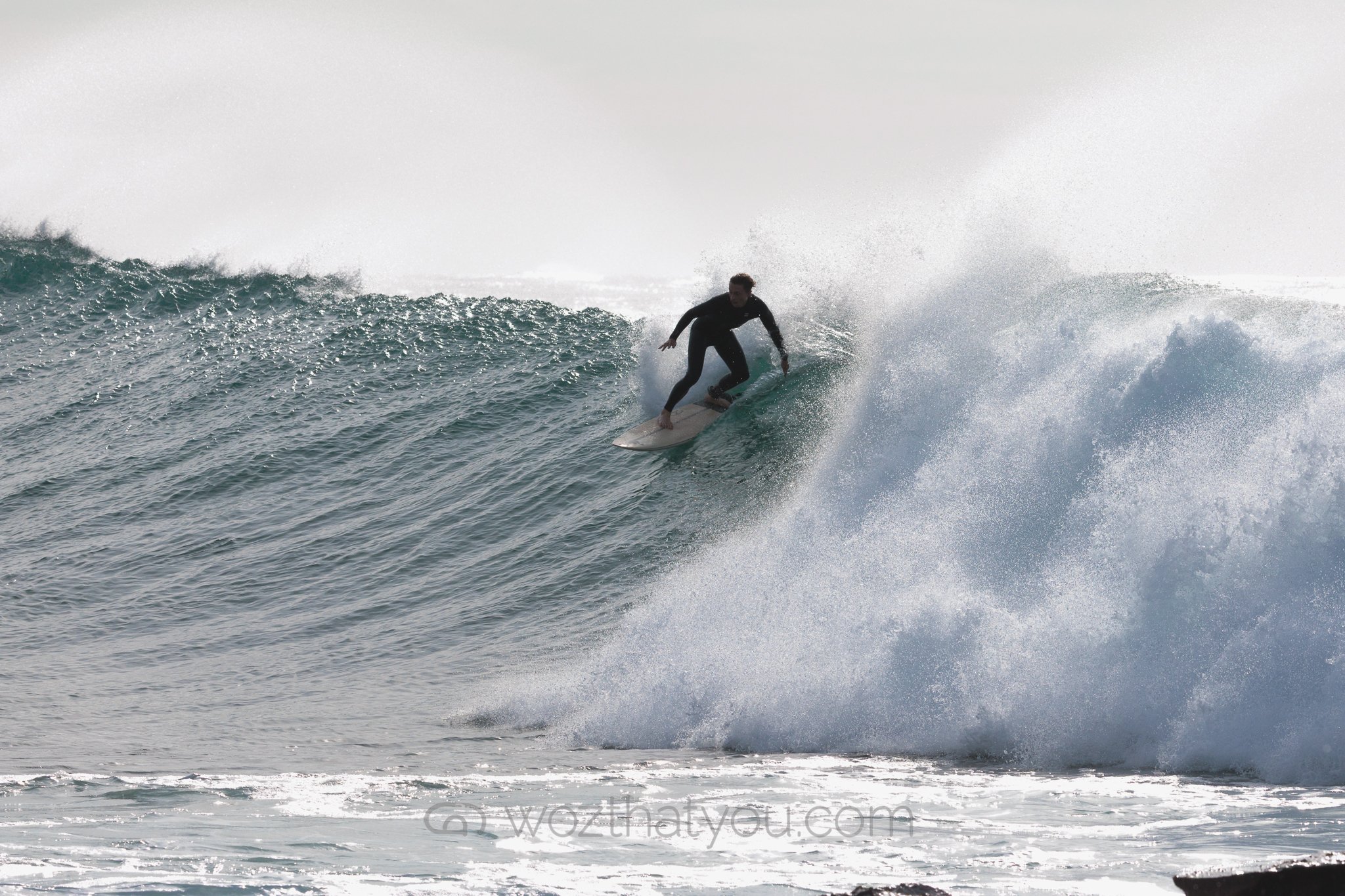 A person surfing on a large wave in the ocean.