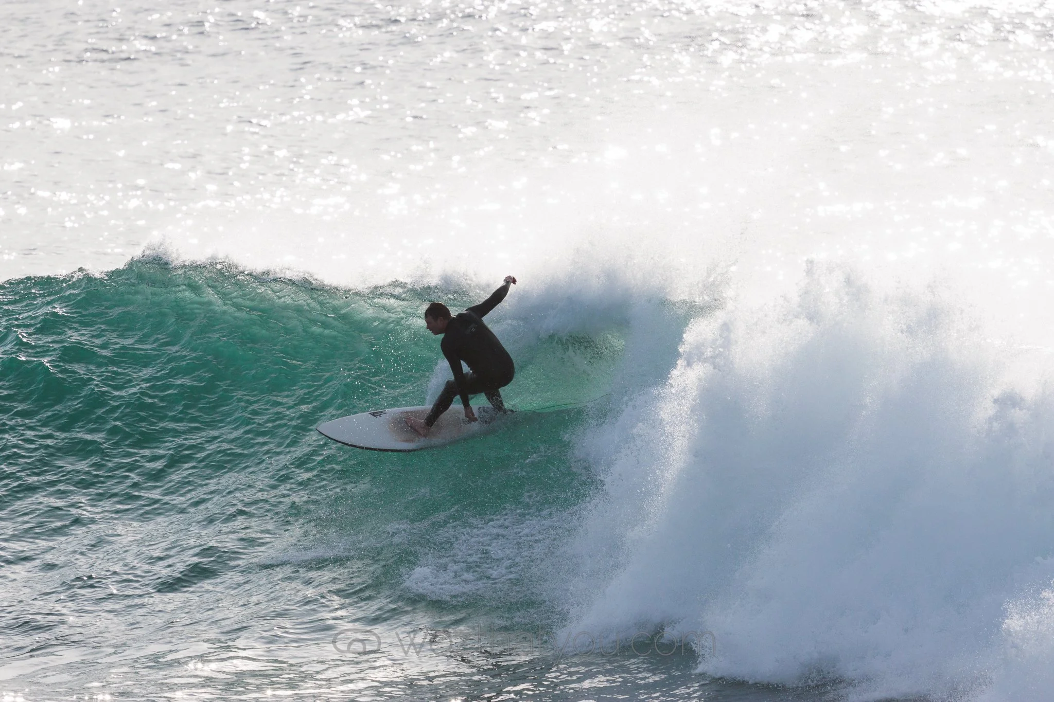 Person wearing black wetsuit surfing on a wave in the ocean