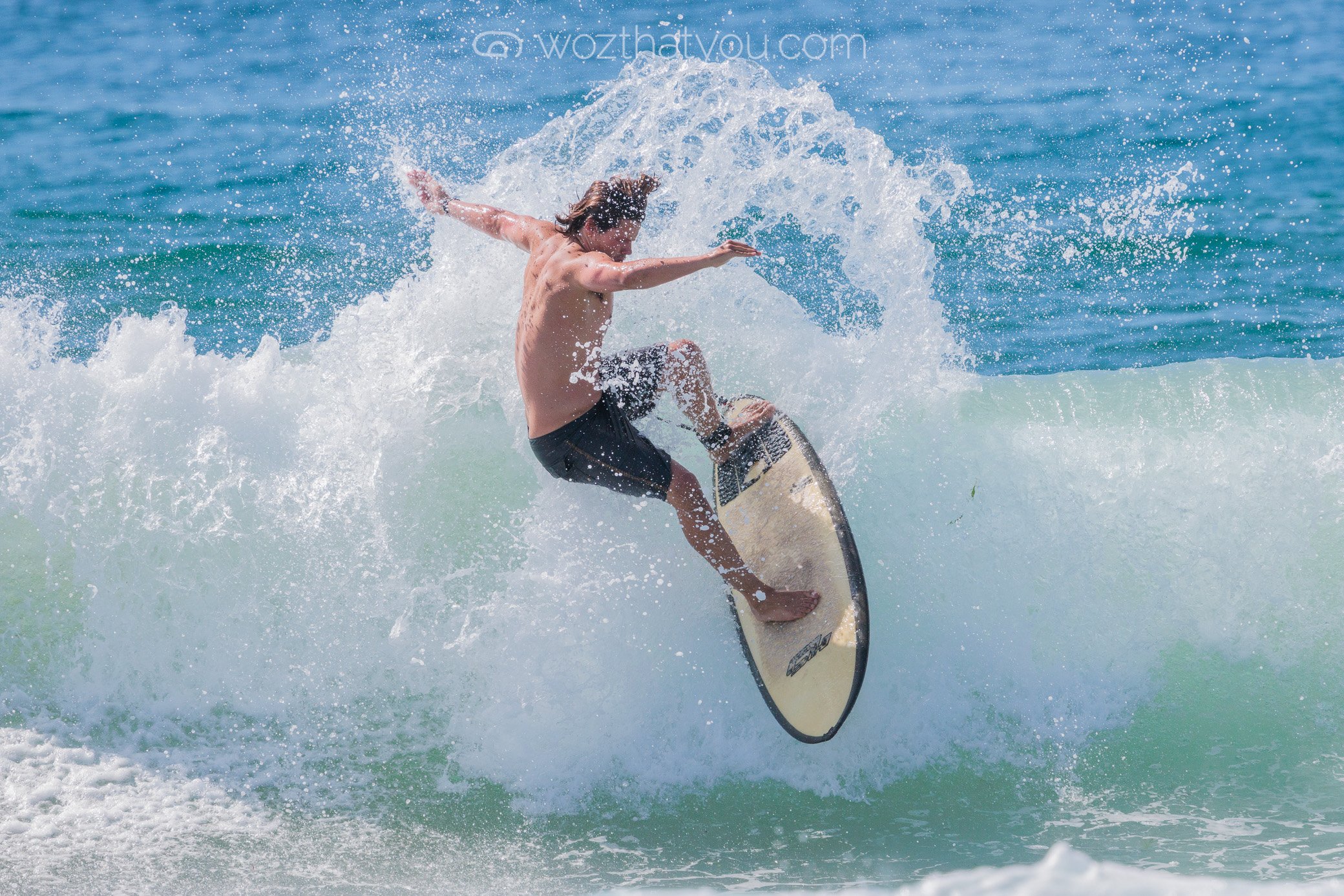 A male surfer riding a wave on a surfboard at the beach.
