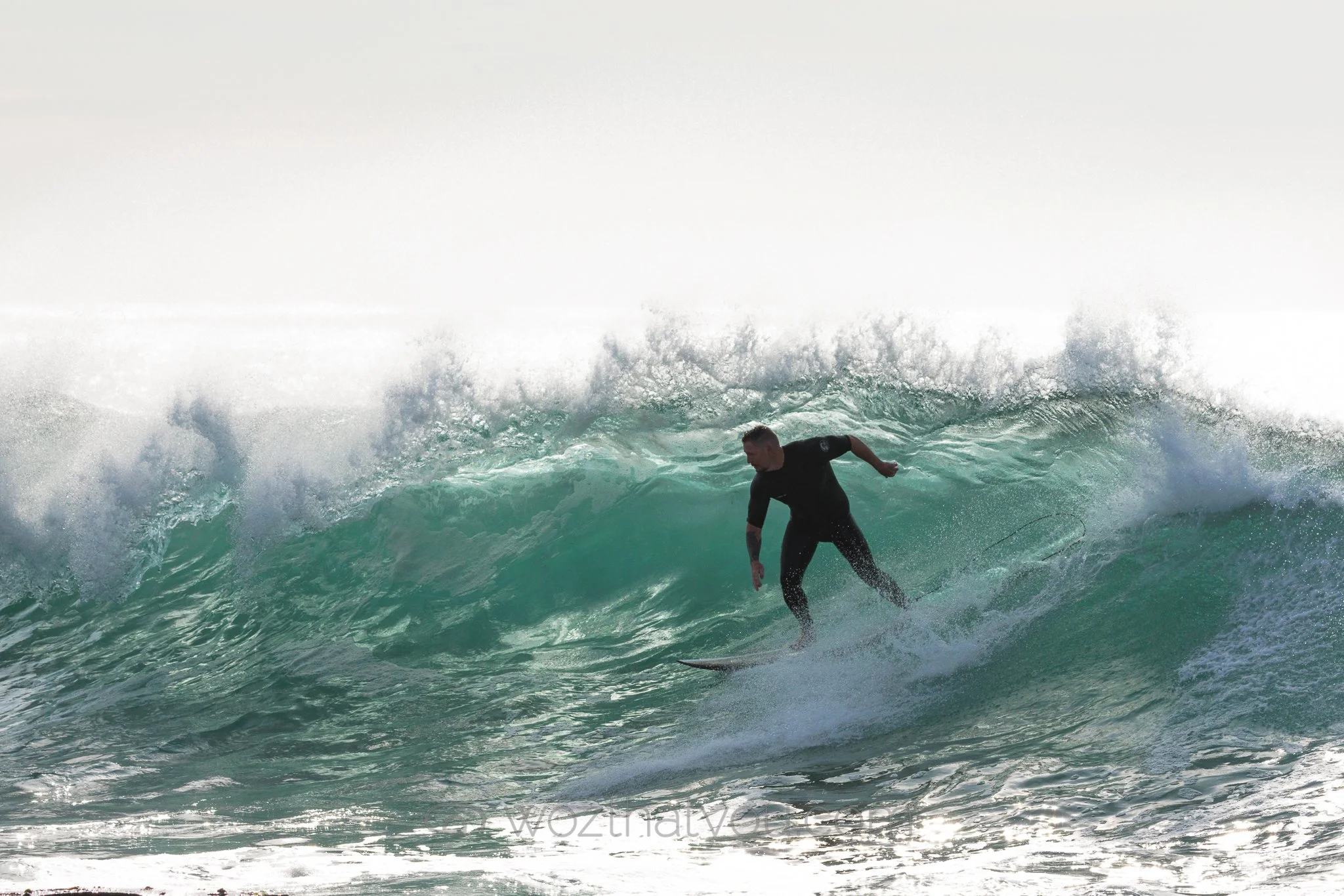 A male surfer riding a wave in the ocean during daylight.