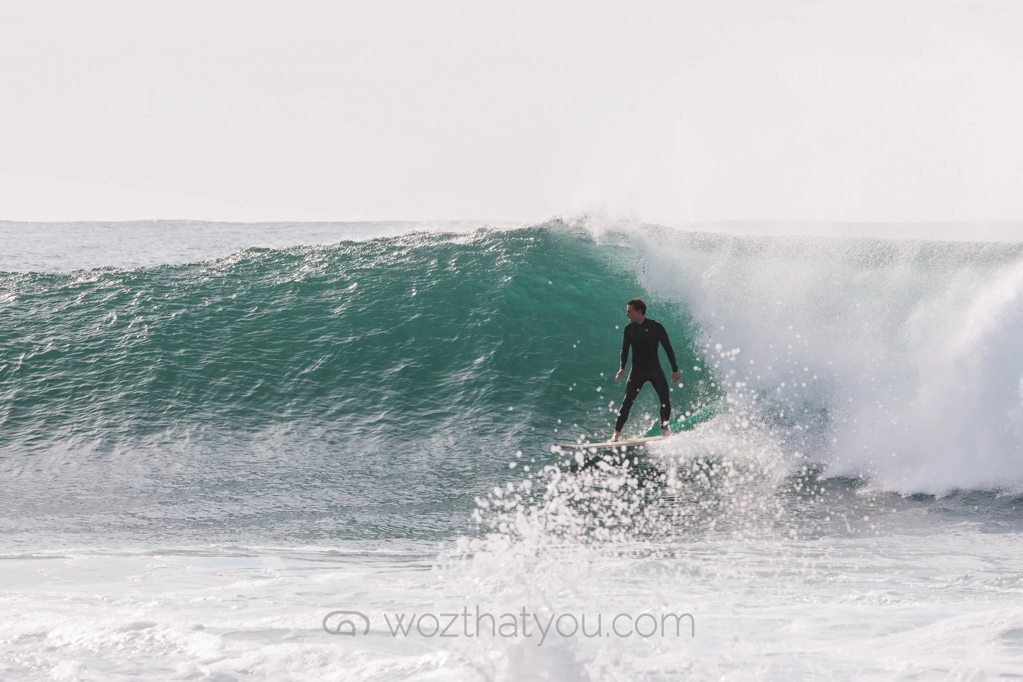 A person in a black wetsuit surfing on a wave in the ocean.