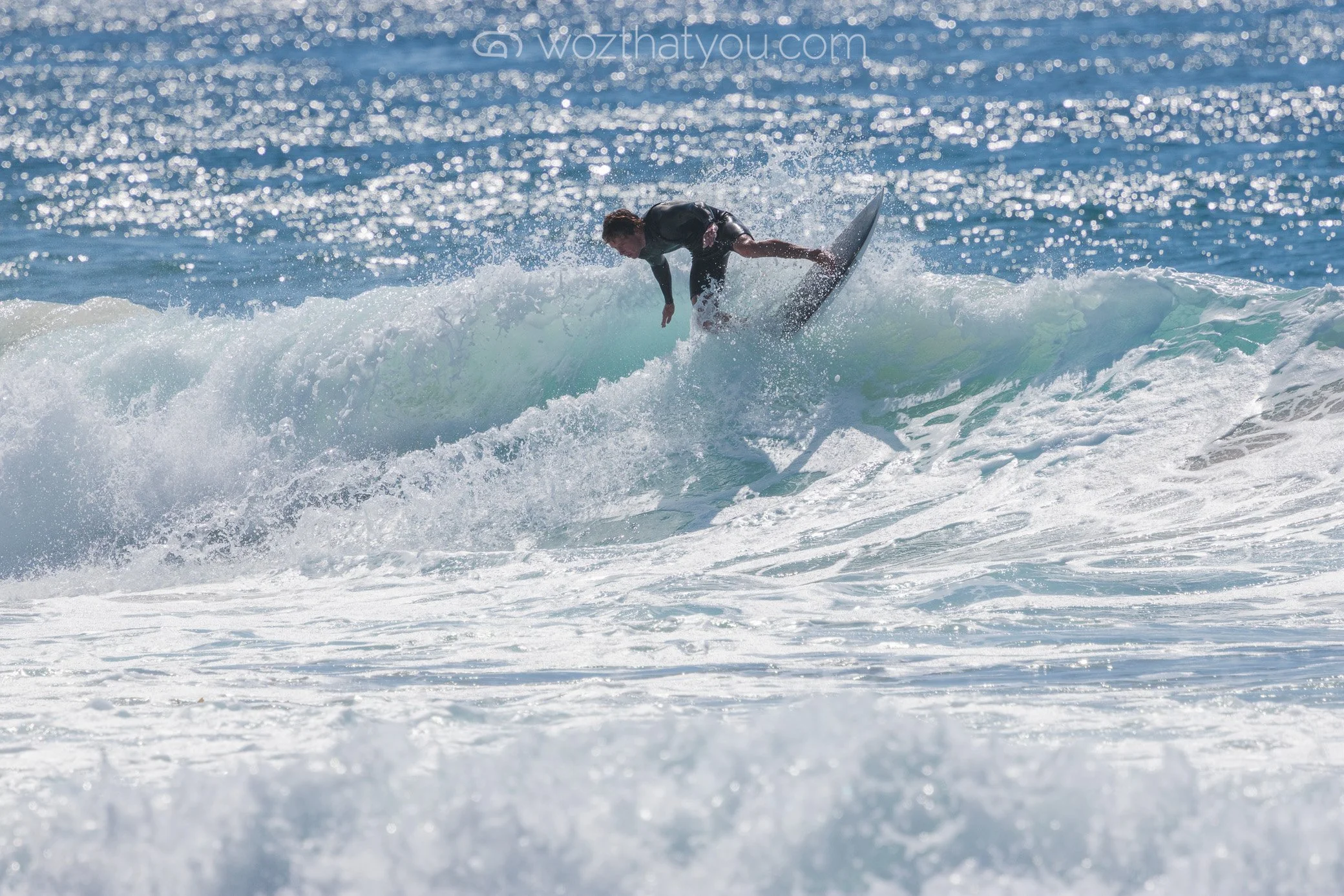 A person in a wetsuit riding a wave on a surfboard in the ocean.