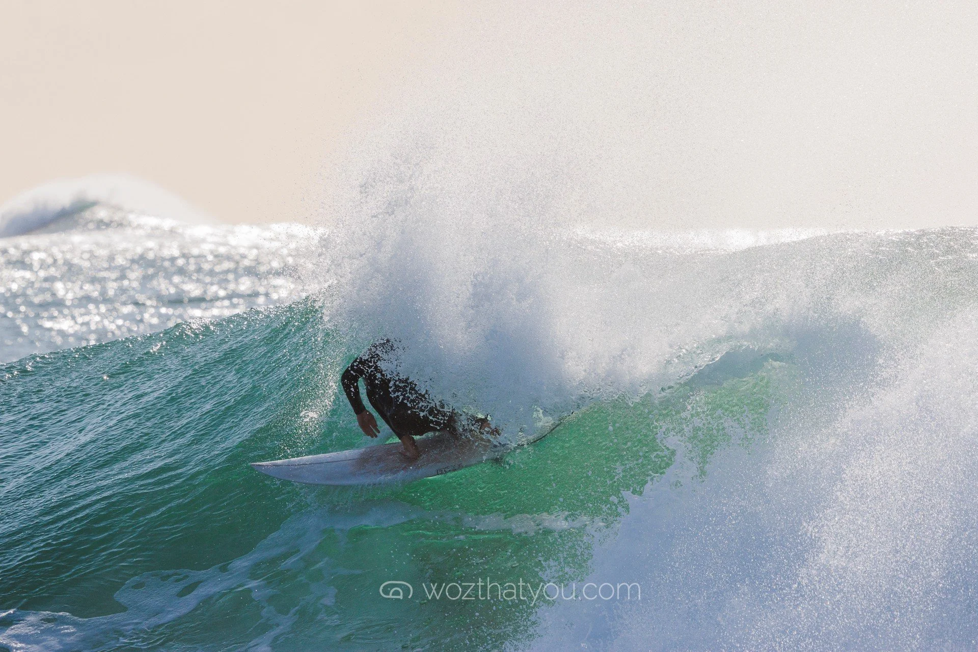 A surfer riding a wave with water splashing around, captured during daytime.