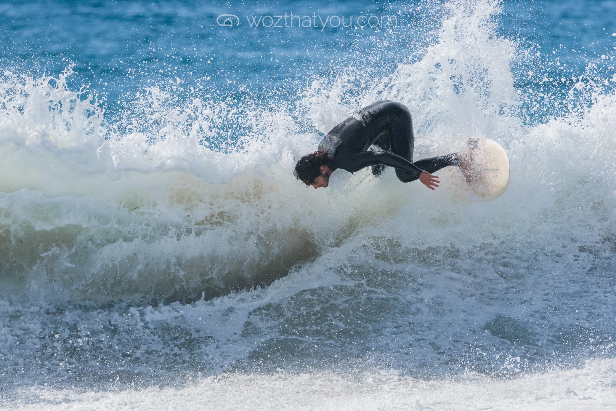 A person in a wetsuit riding a wave on a surfboard.