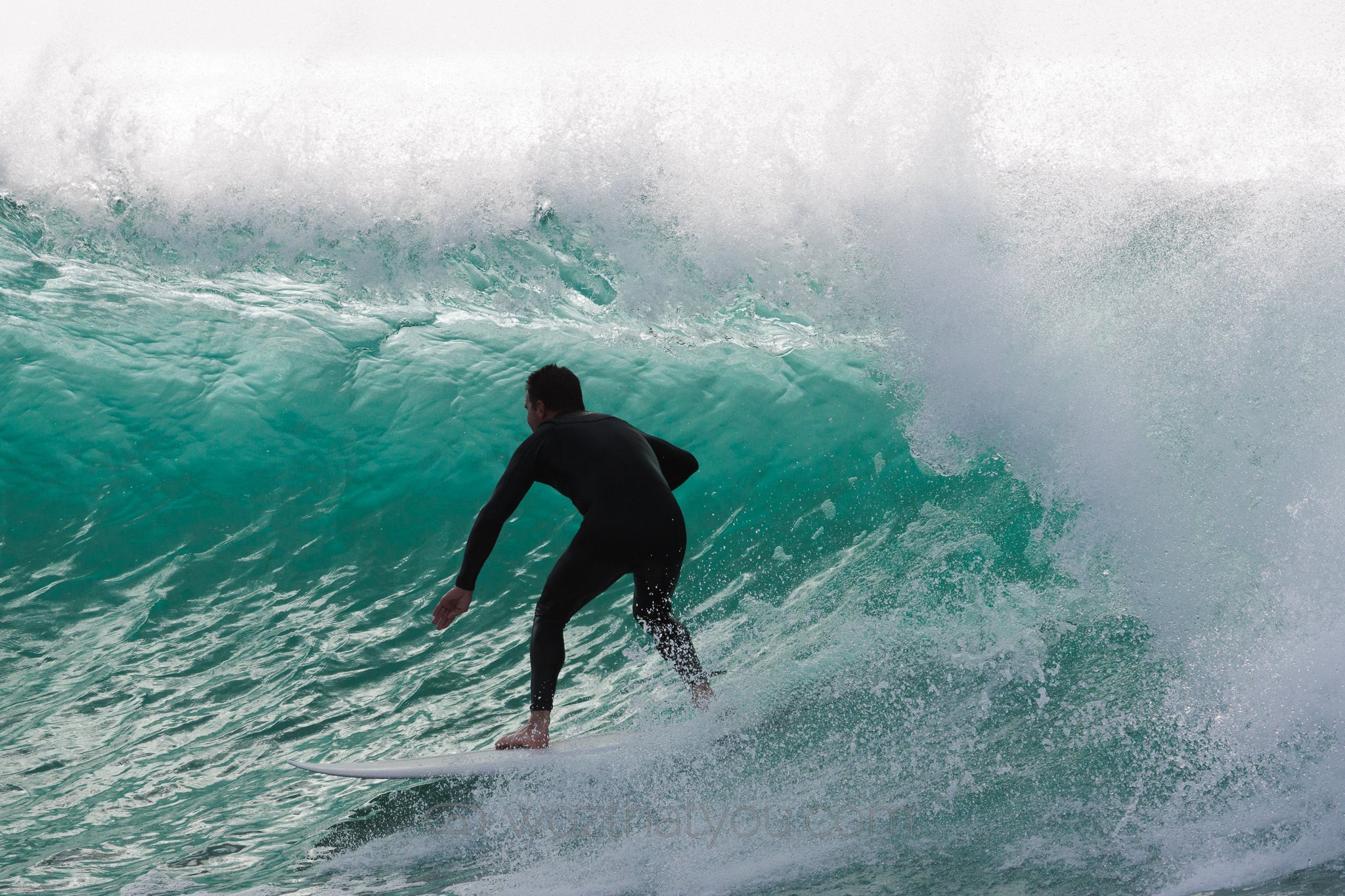 A person surfing on a large wave in the ocean.