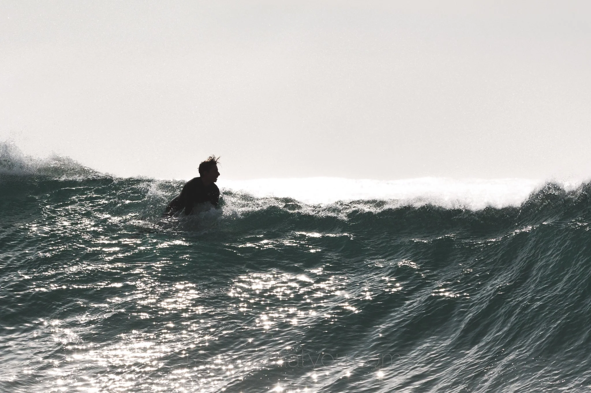 Person surfing on a wave in the ocean.