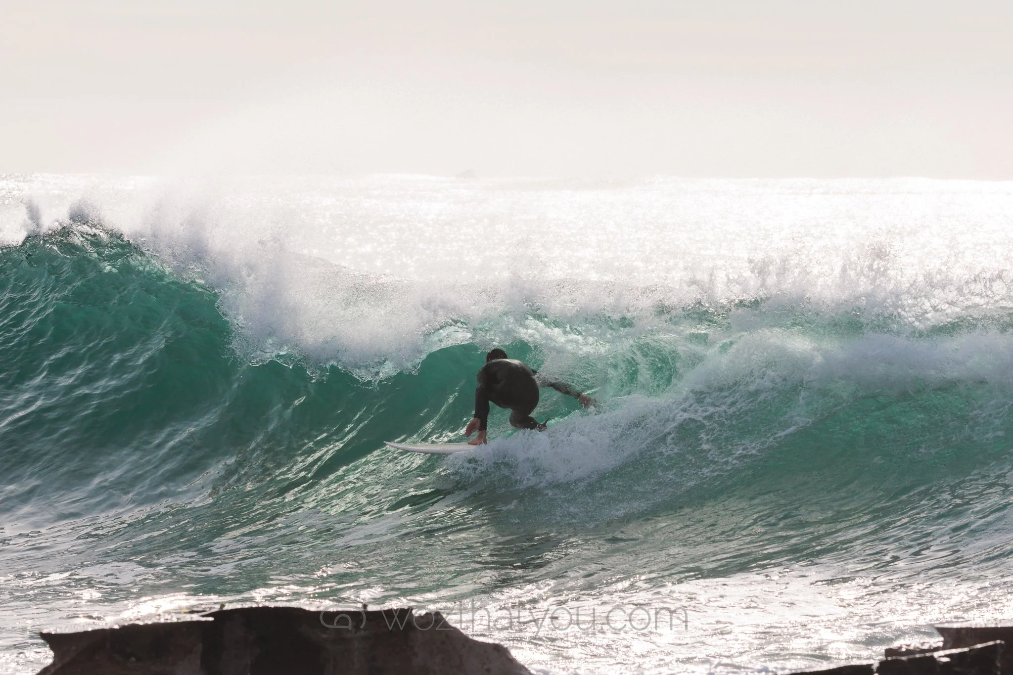 A person surfing on a wave in the ocean during daylight