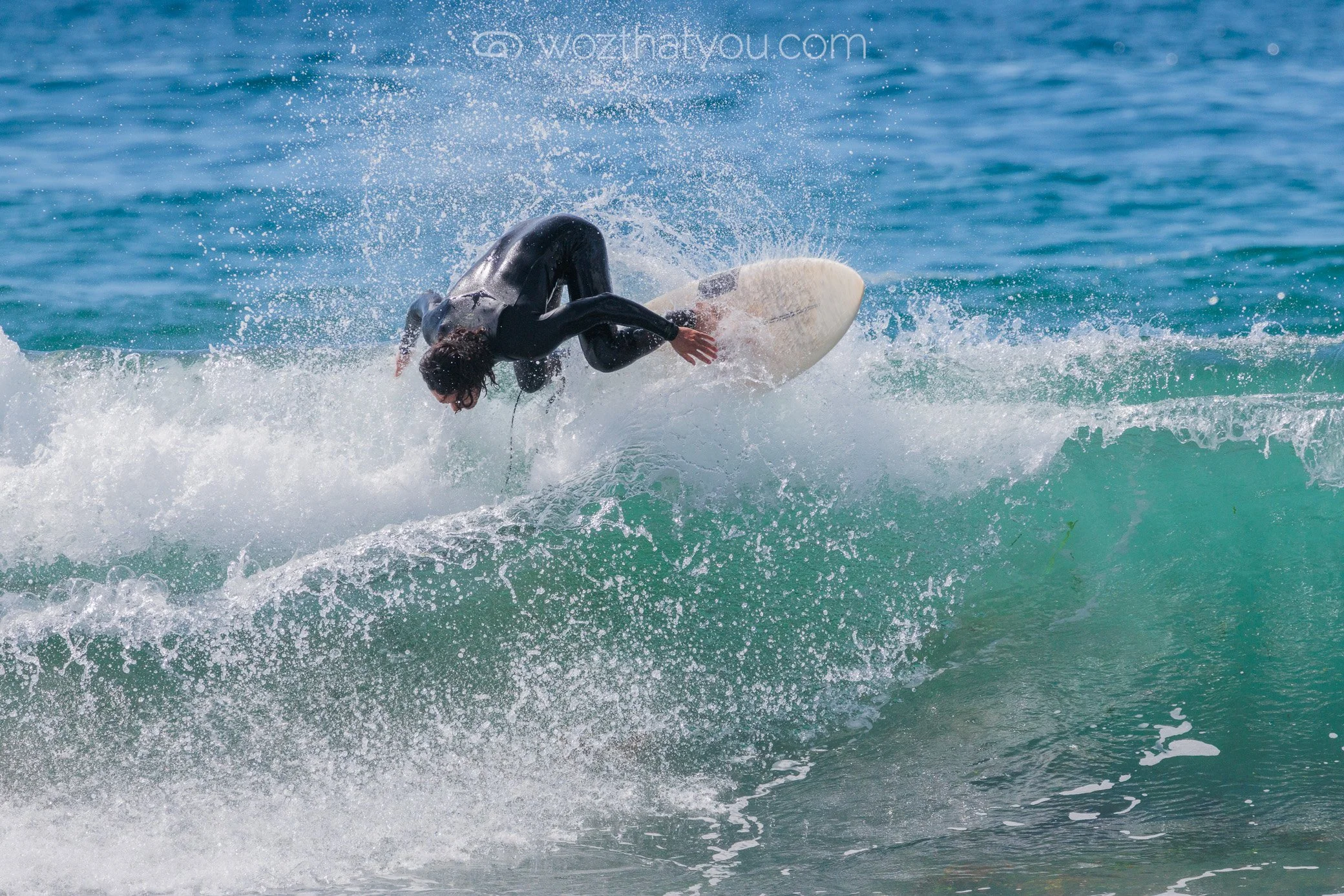 Surfer performing an acrobatic maneuver on a wave in the ocean.