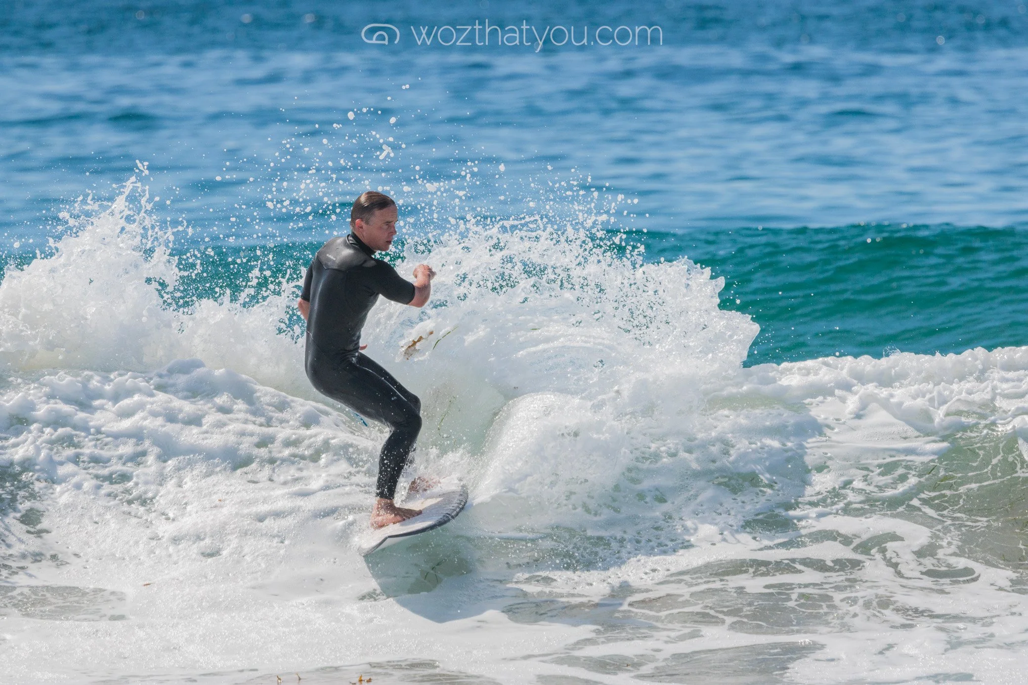 Person wearing a wetsuit surfing on a wave in the ocean.