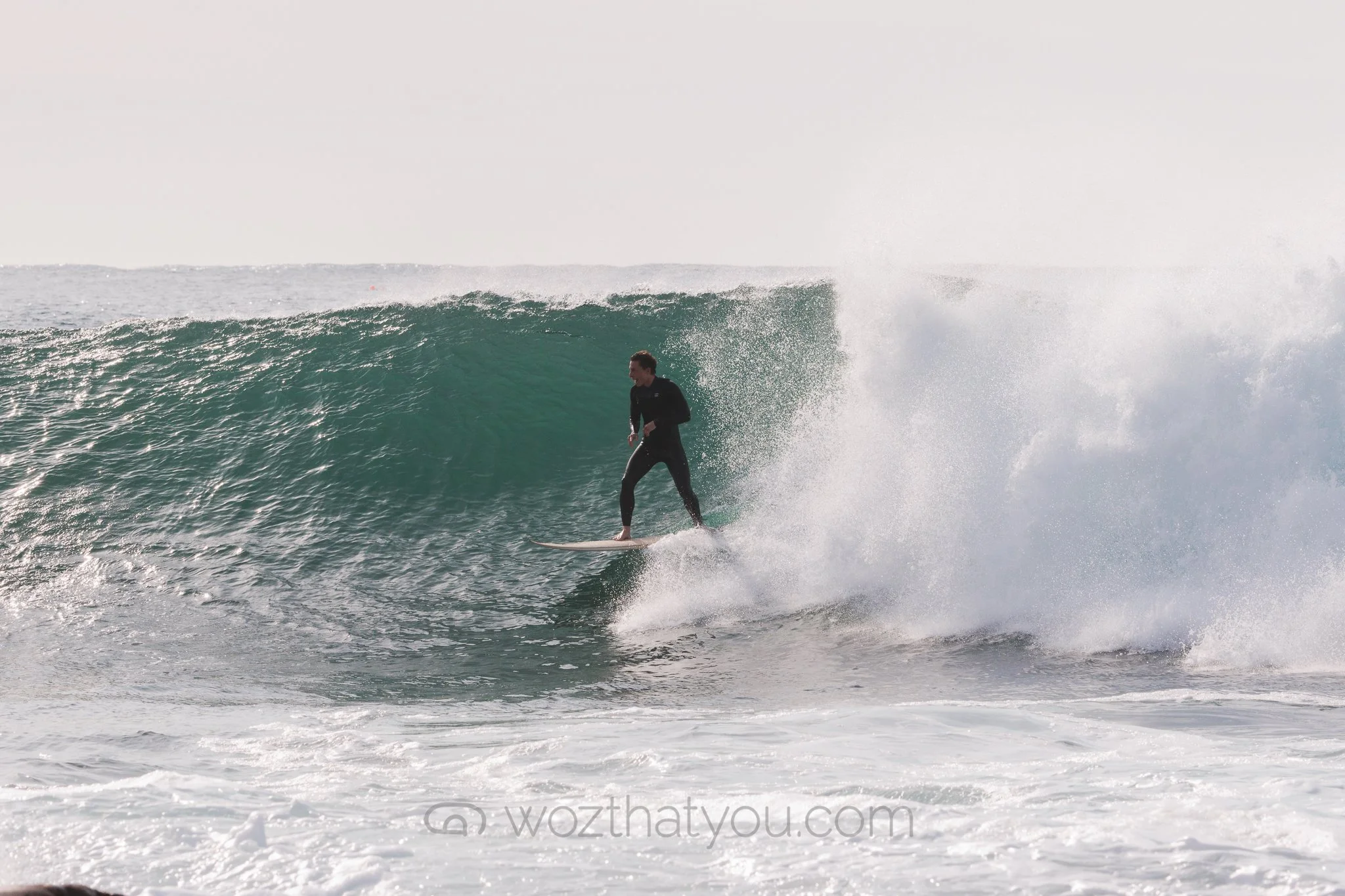 A person surfing on a large wave in the ocean.