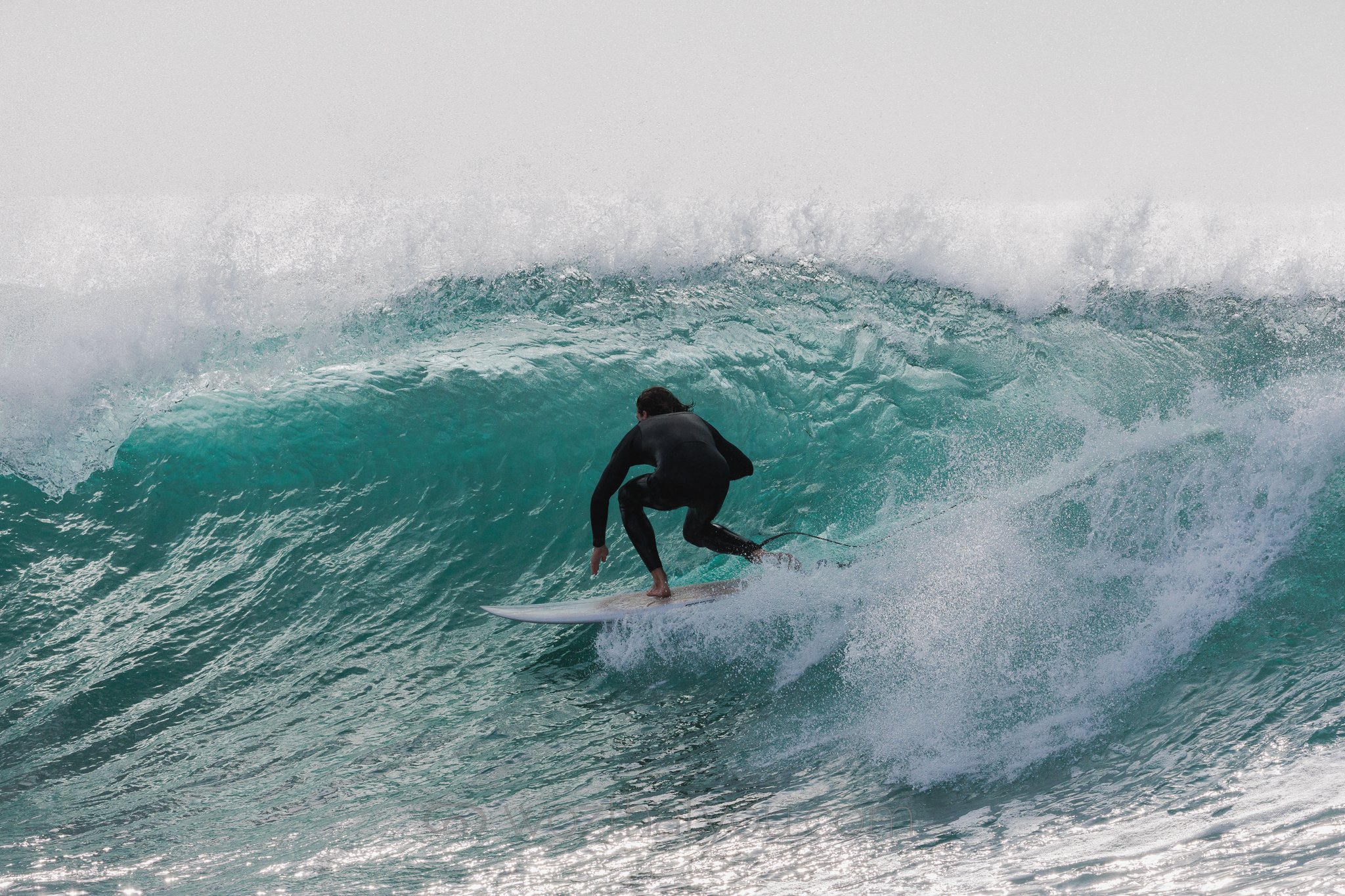 A person in a wetsuit surfing on a large ocean wave.