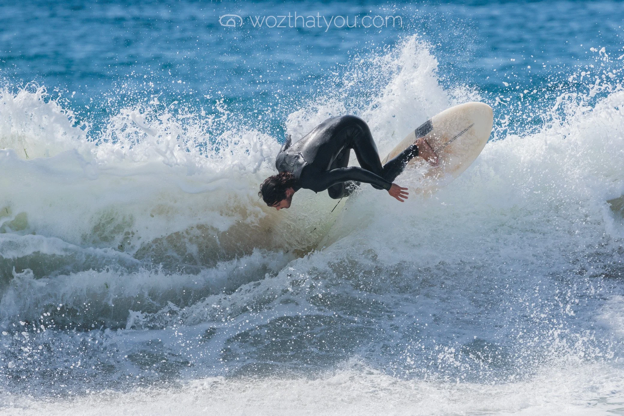 A person in a wetsuit surfing on a wave in the ocean.