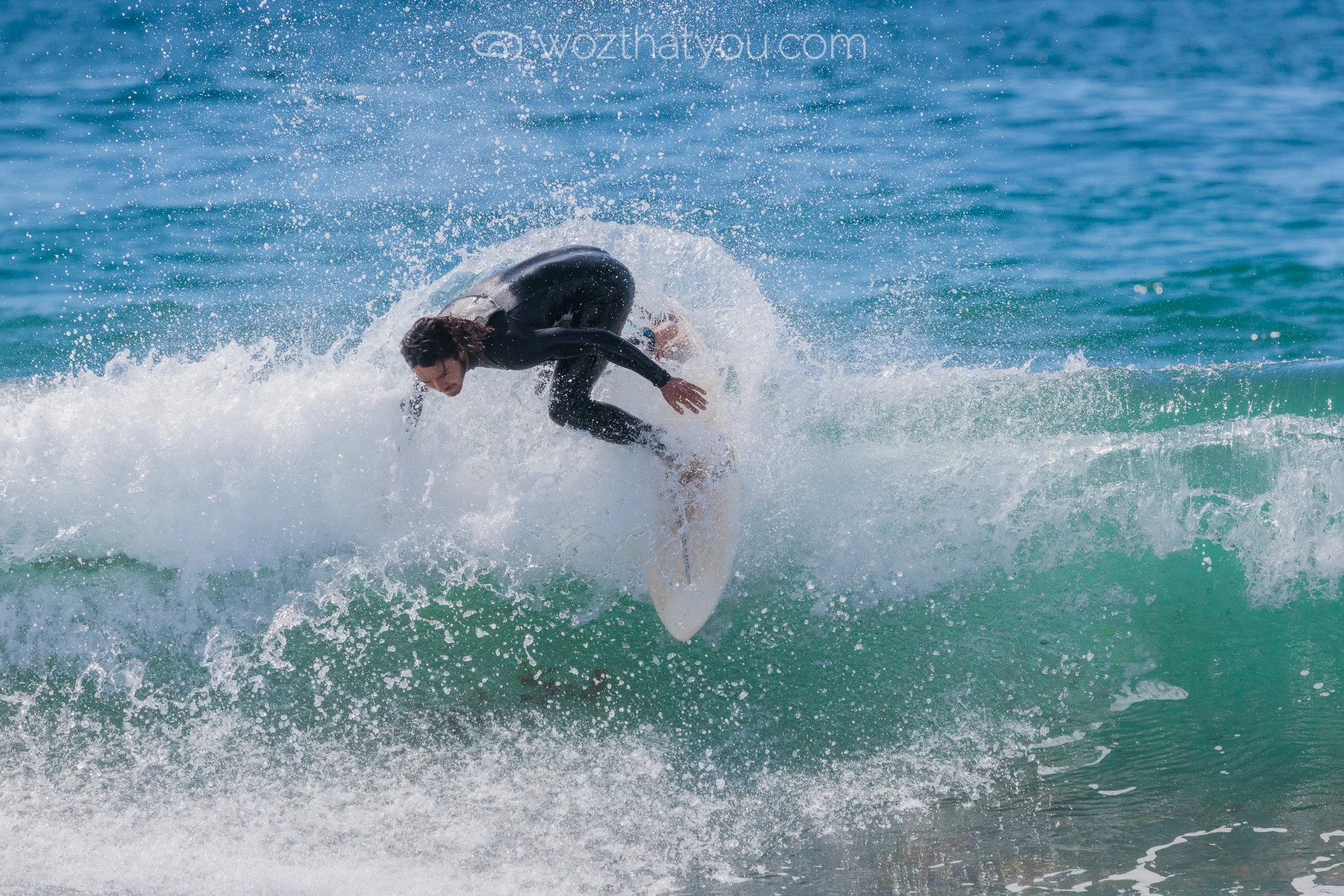 Person riding a surfboard on a wave with water splashing around.
