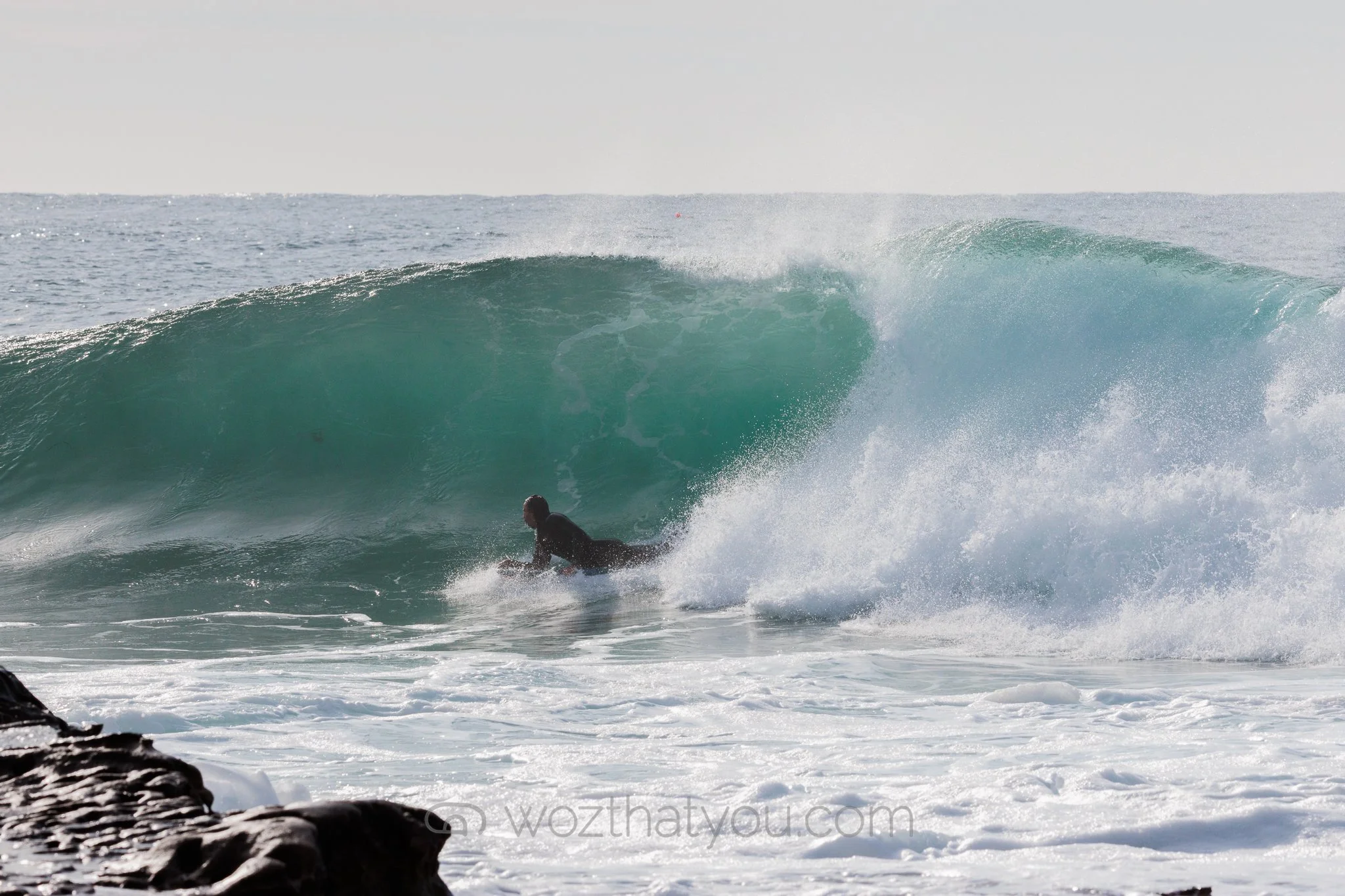 A person surfing on a large wave in the ocean.