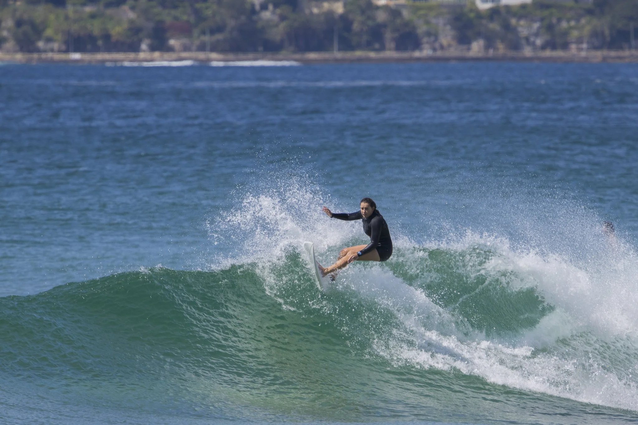 A person surfing on a wave in the ocean near the shoreline.