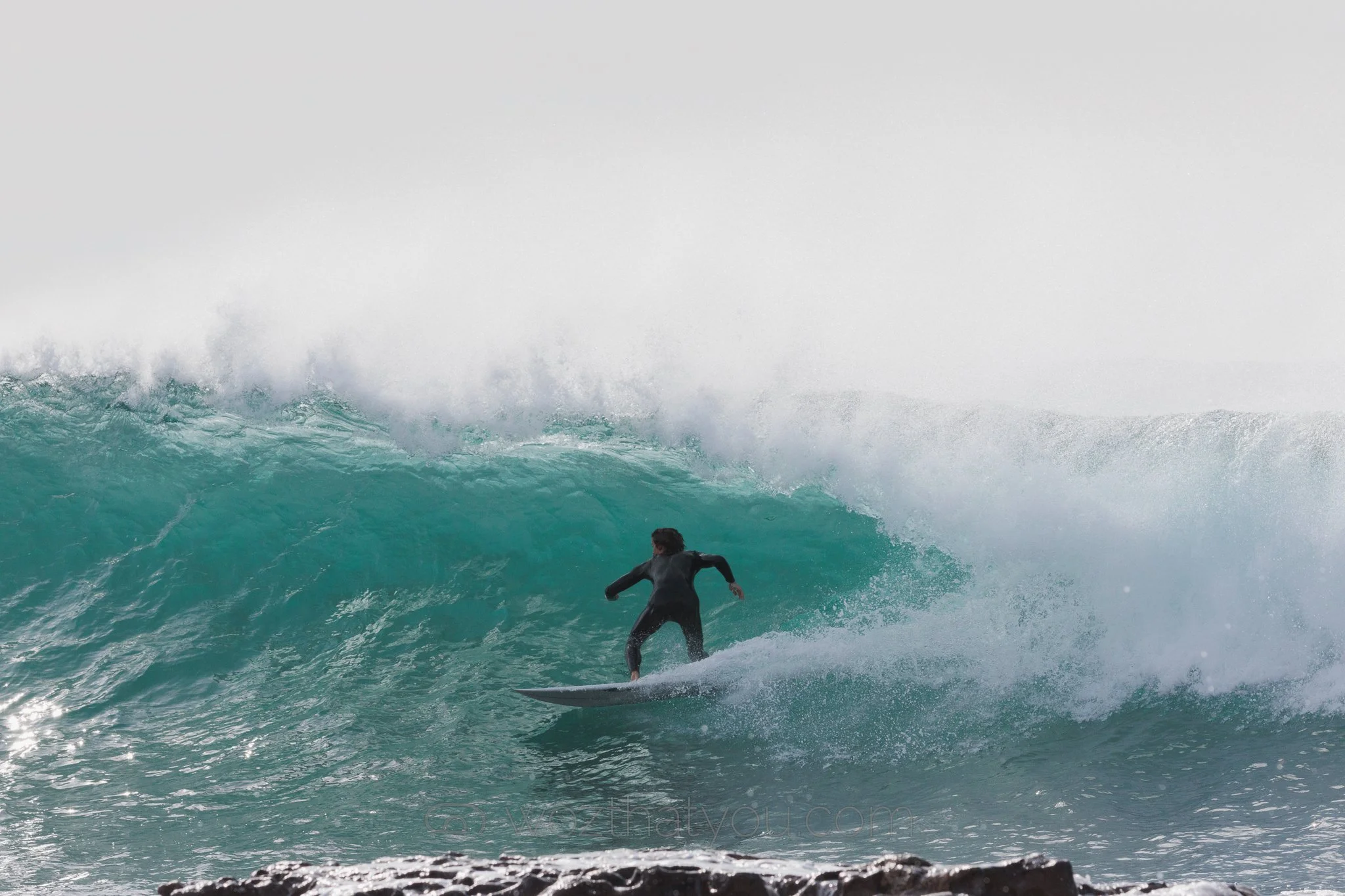 A person surfing on a large ocean wave.