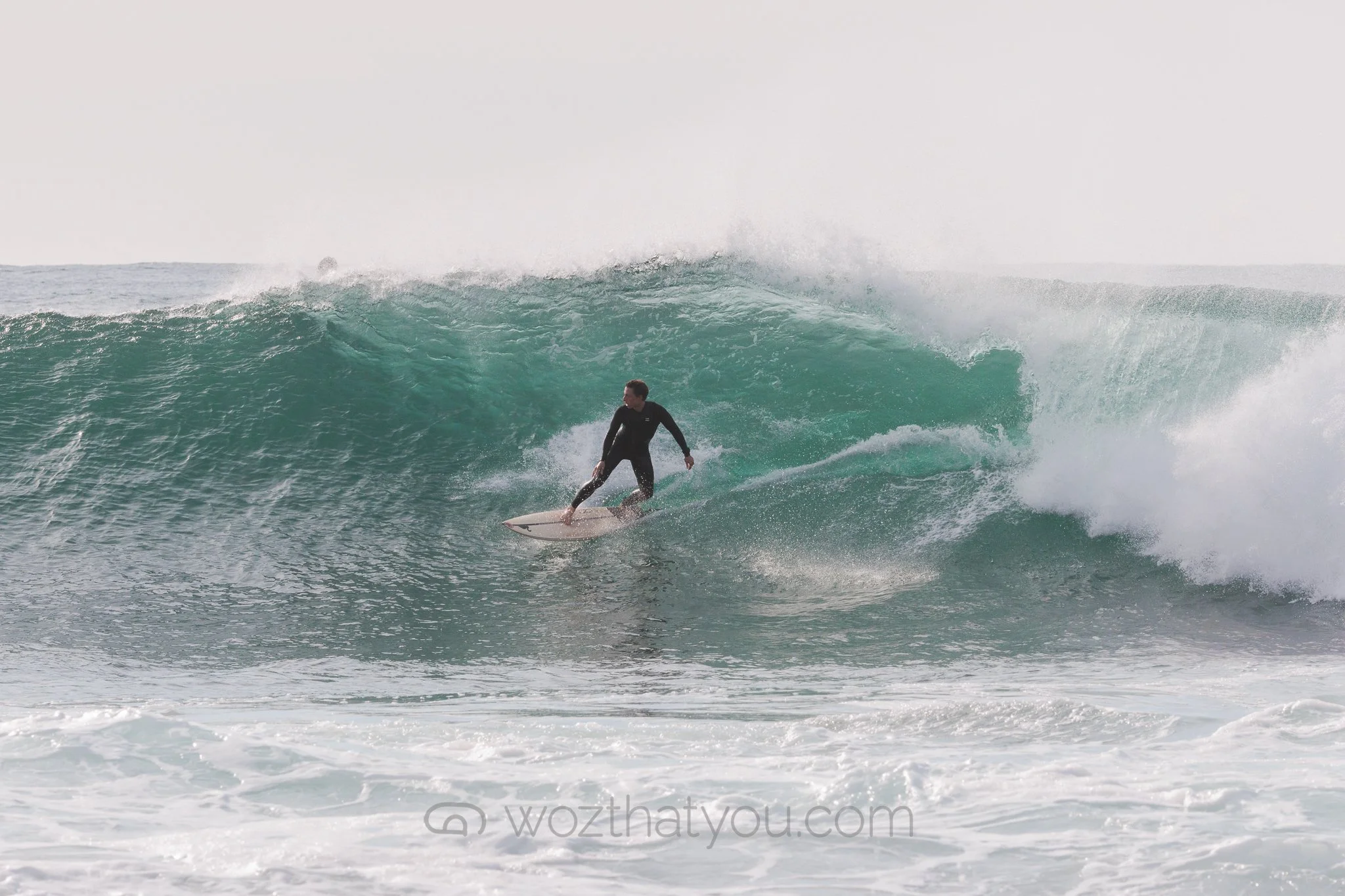 A person surfing on a large ocean wave during daytime.