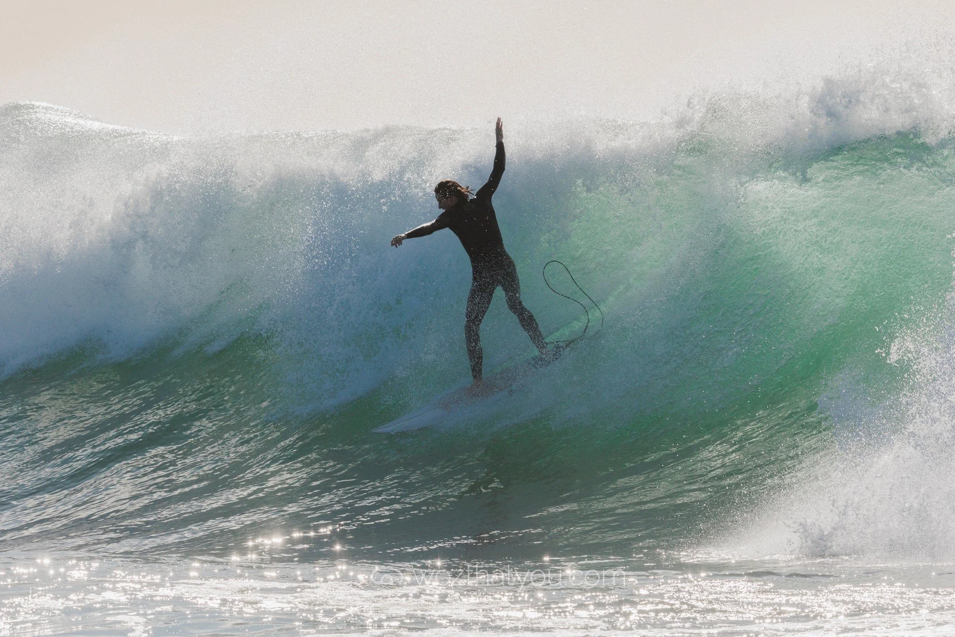 Person surfing on a large wave in the ocean.