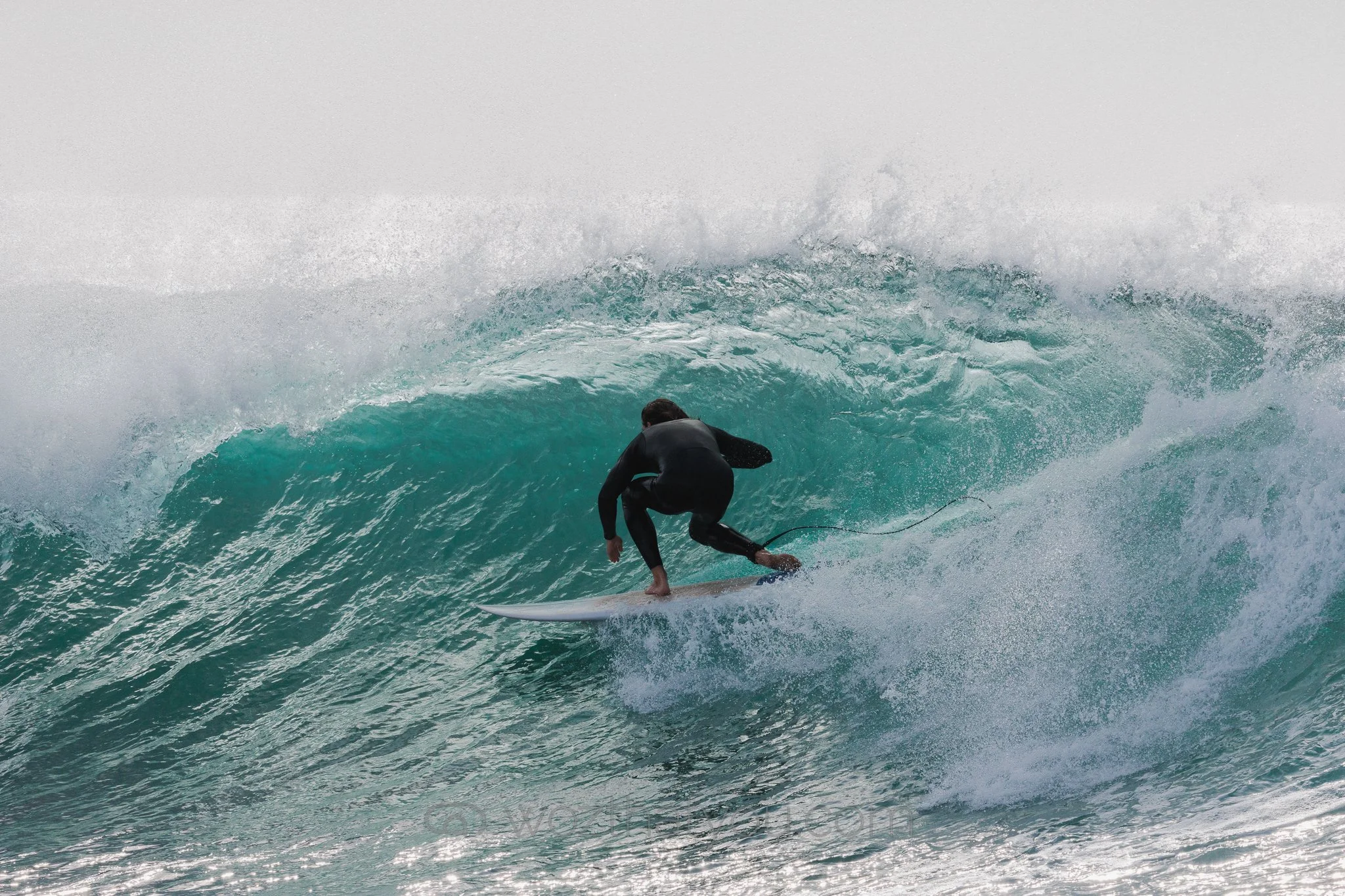 A person surfing on a large wave in the ocean.