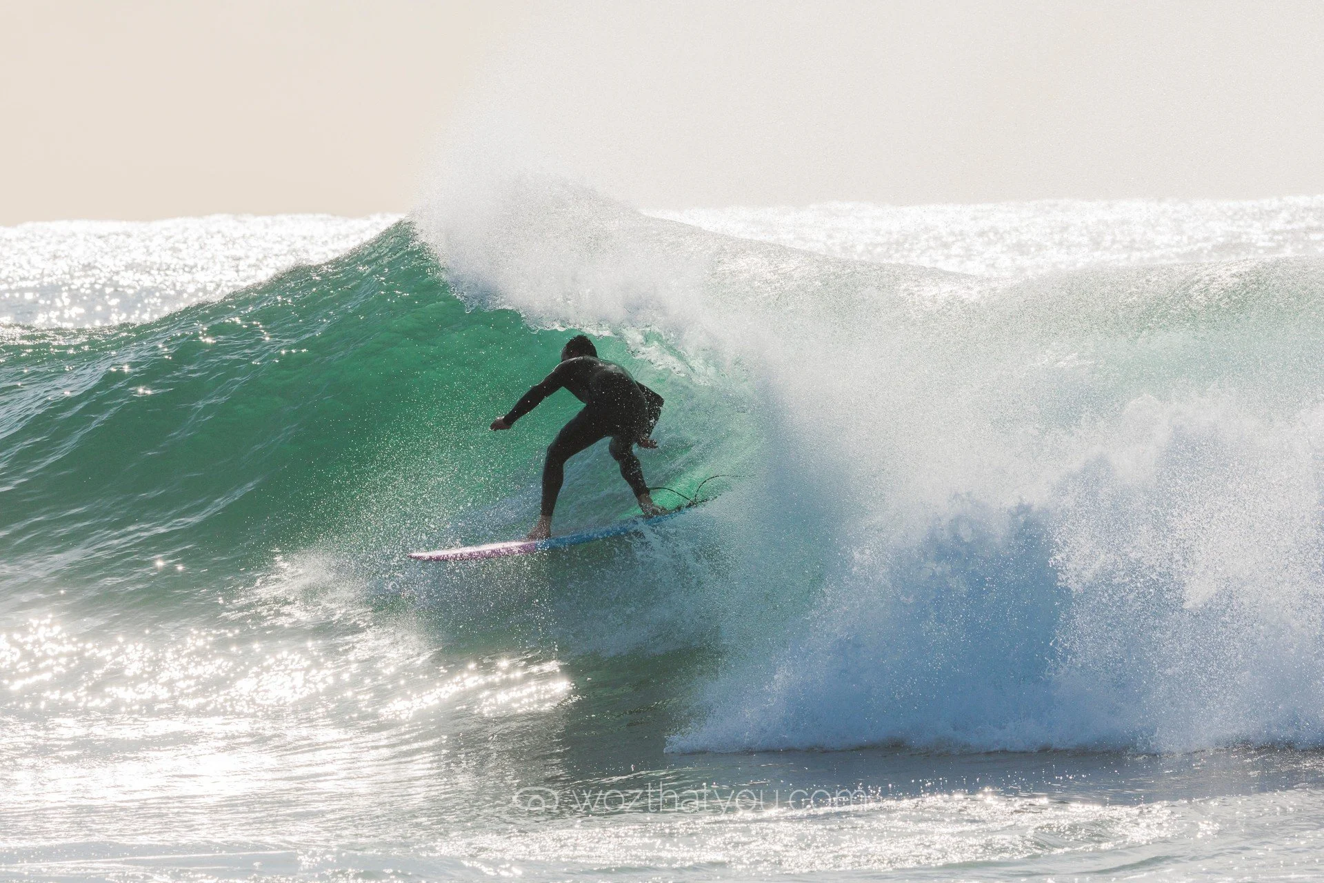 A person surfing on a large wave in the ocean during daylight.