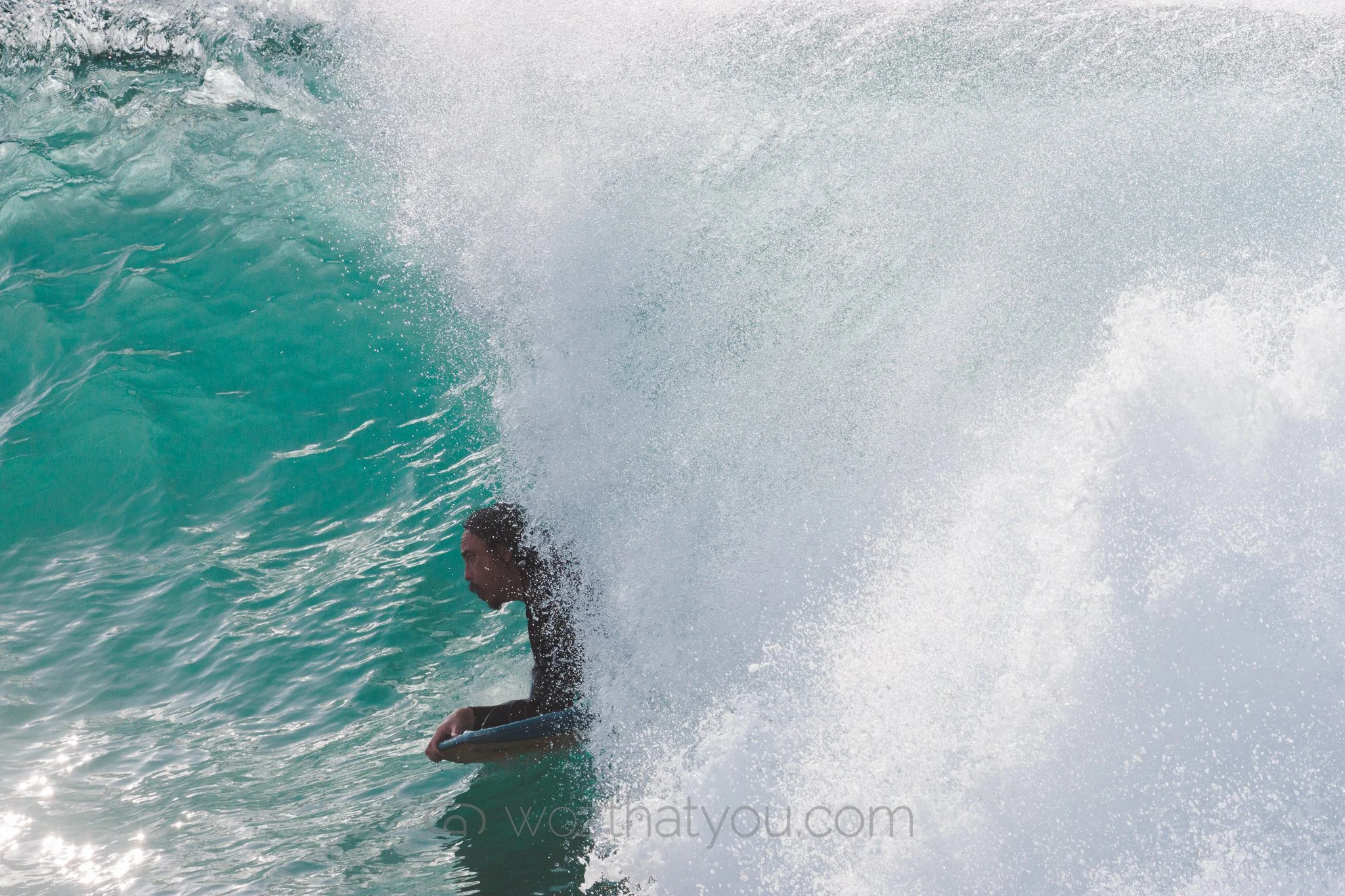 A person riding inside a large wave on a surfboard in the ocean.