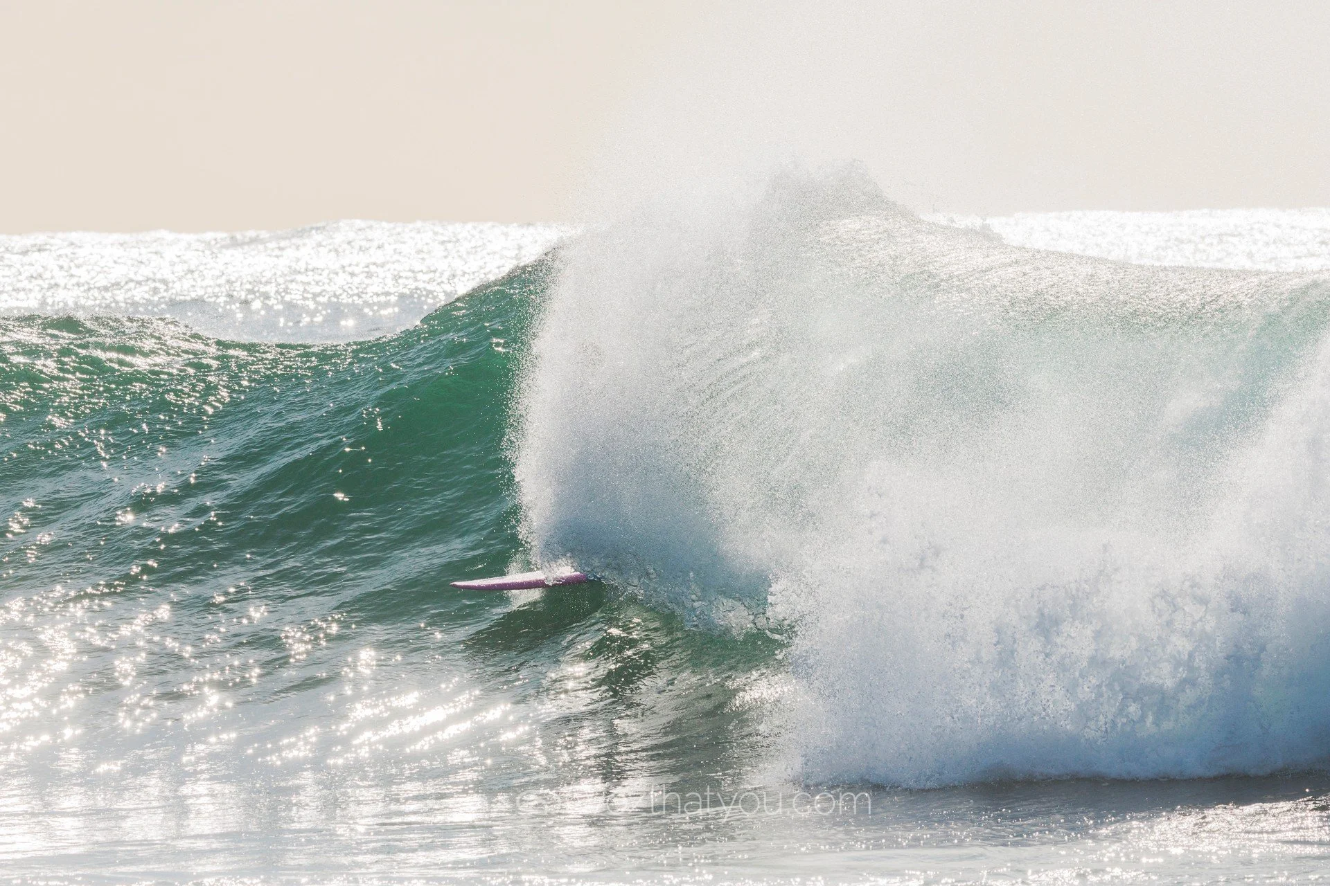 A person surfing on a large ocean wave during the daytime.