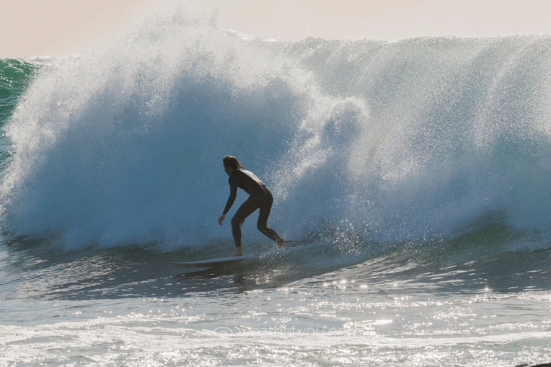 Person surfing on a large wave at the beach during daylight.