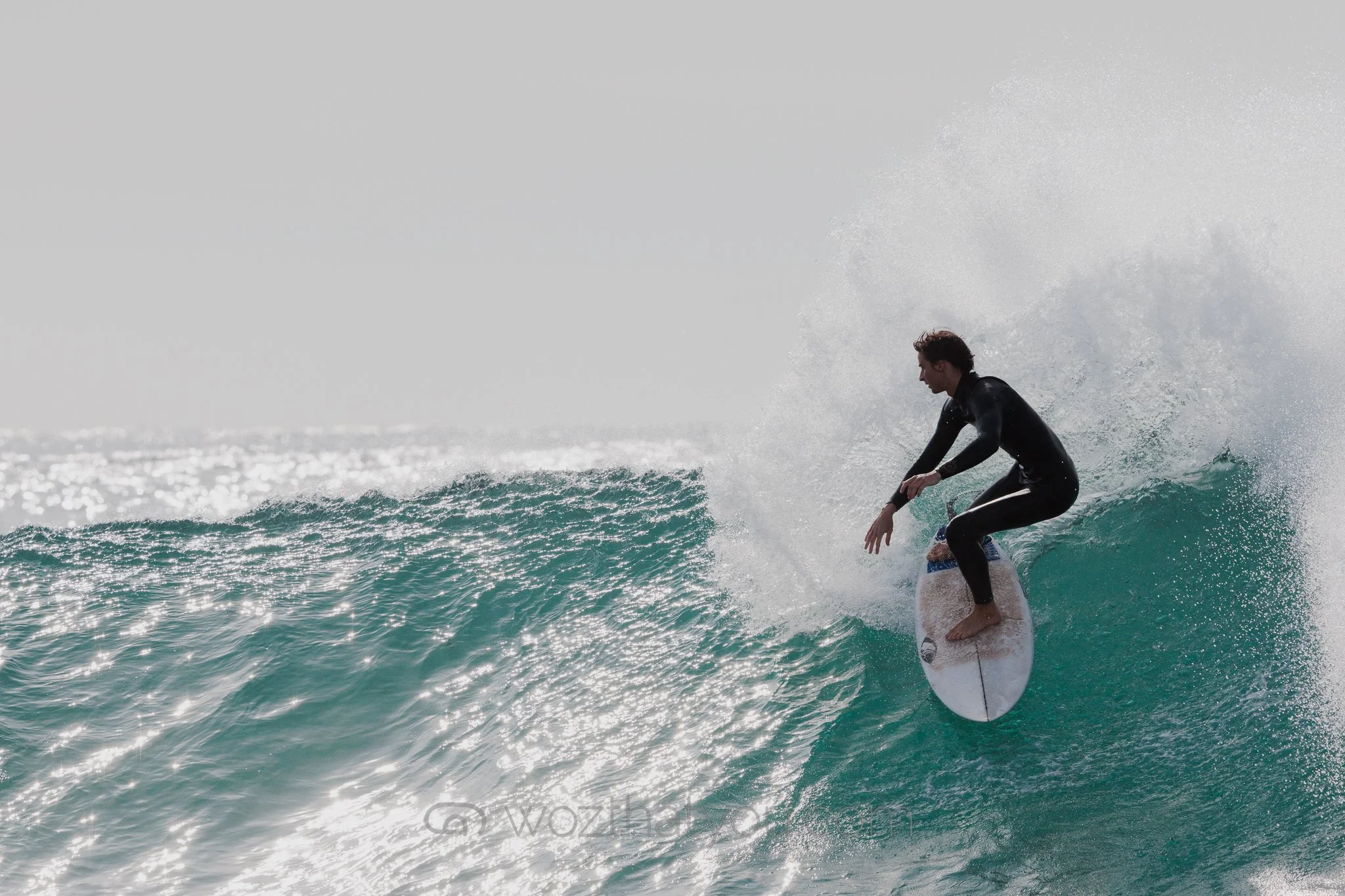 A person in a black wetsuit surfing on a wave in the ocean.