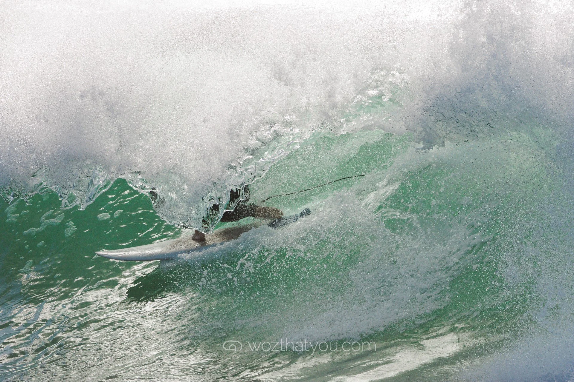 A surfer riding inside a breaking wave in the ocean.