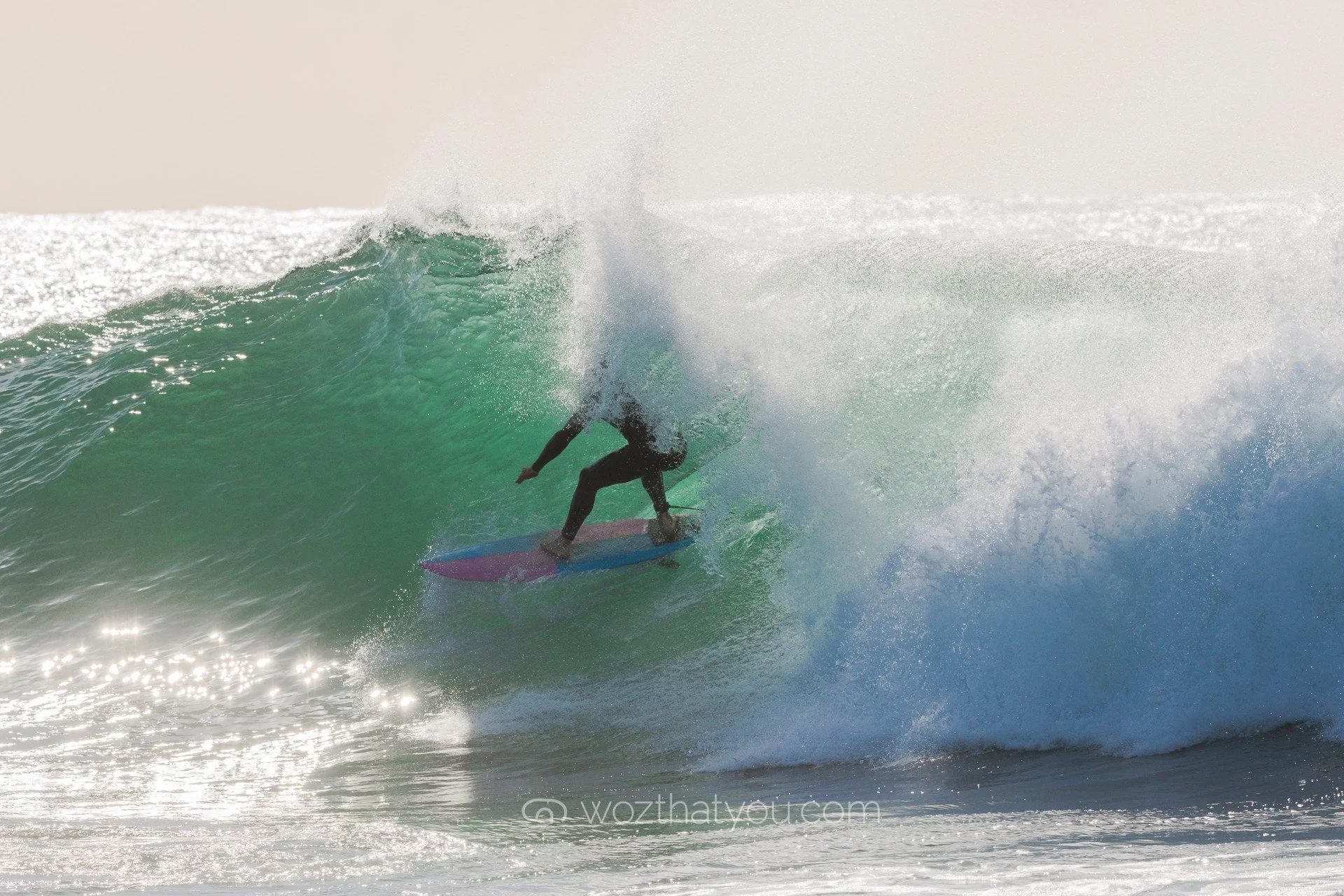 A surfer riding inside a large ocean wave during daylight