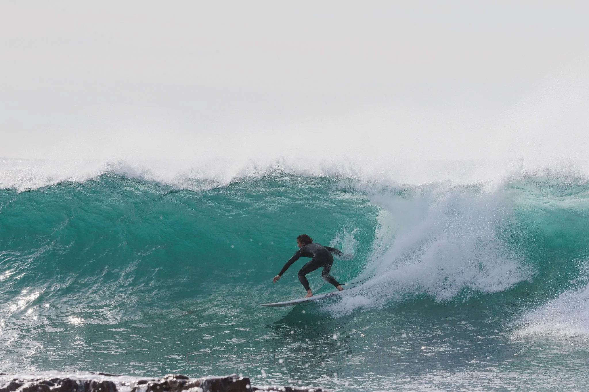 Surfer riding a large ocean wave near the shoreline.